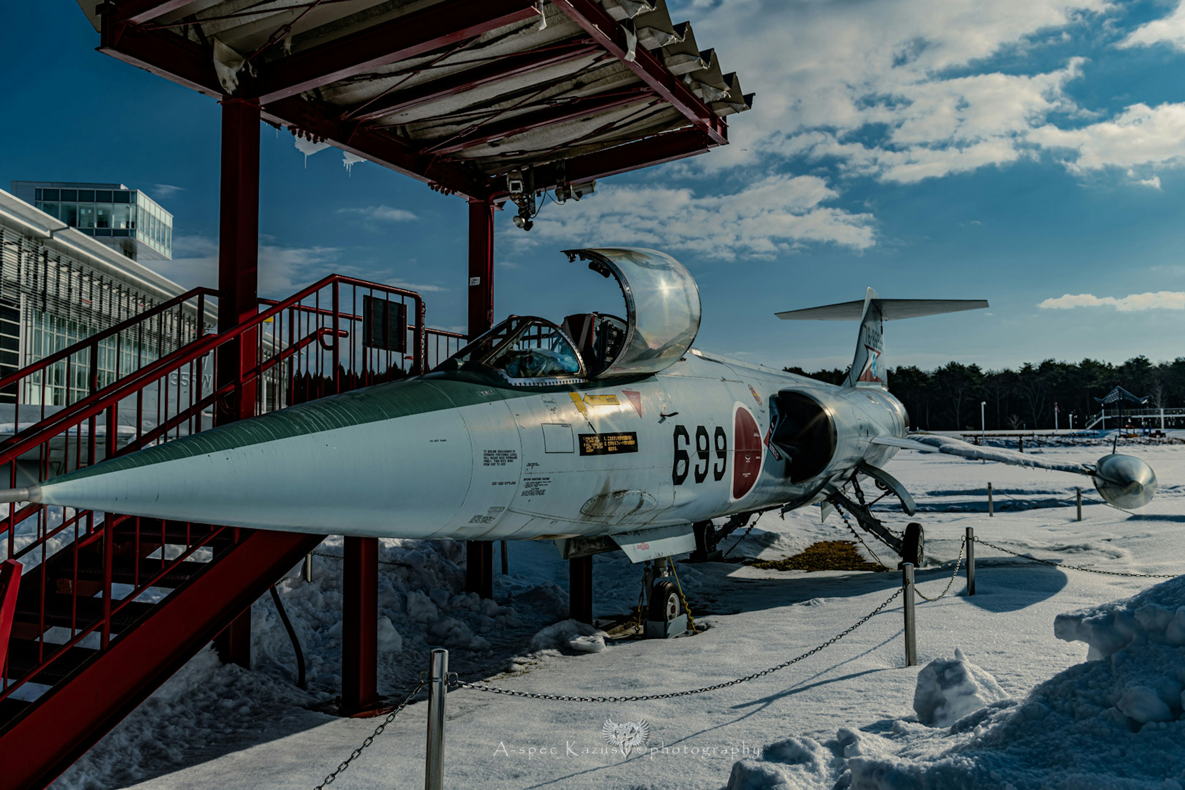 Side view of a fighter jet displayed in a snowy area