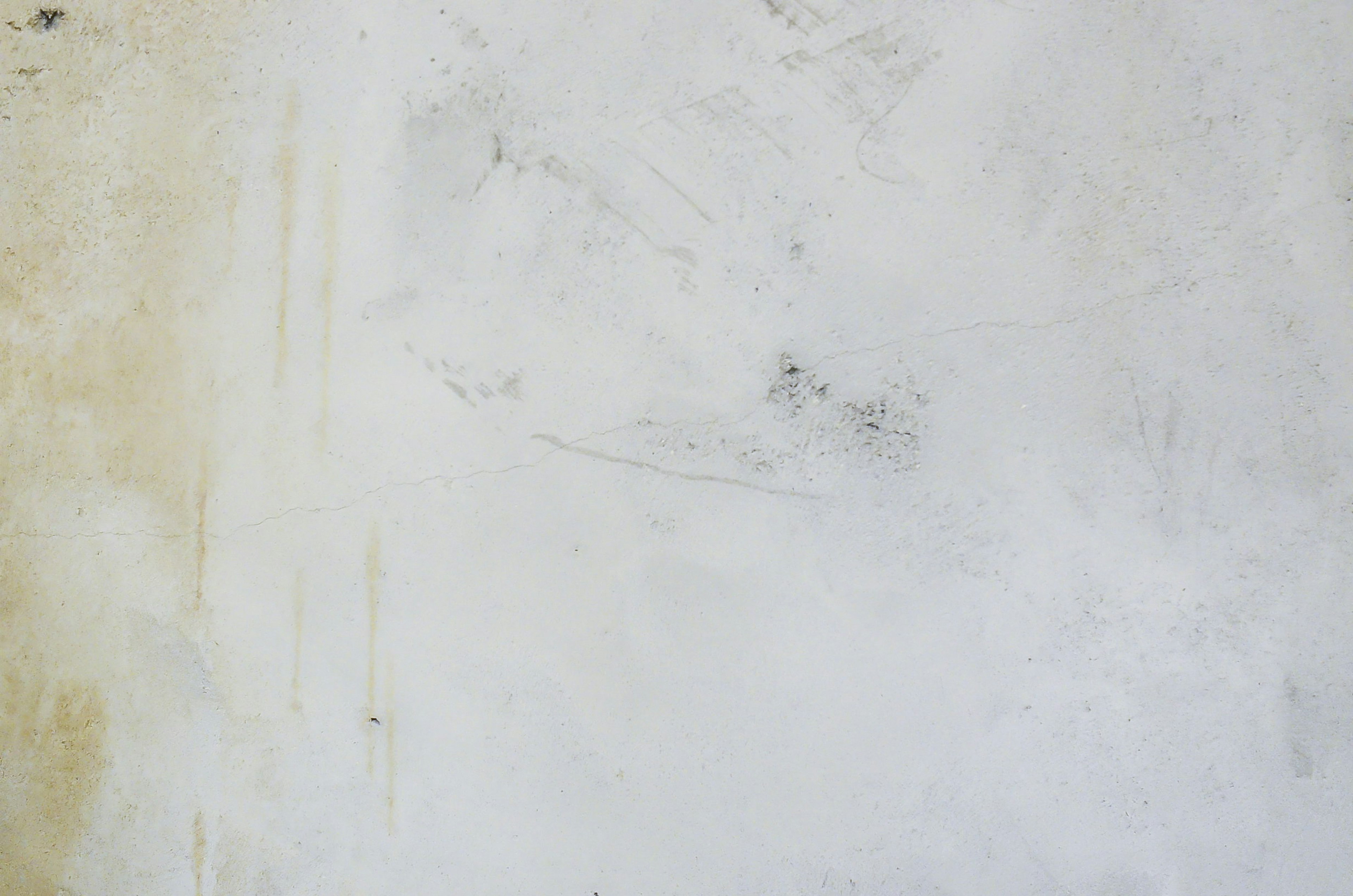 Surface of a white wall with faint brown stains and streaks