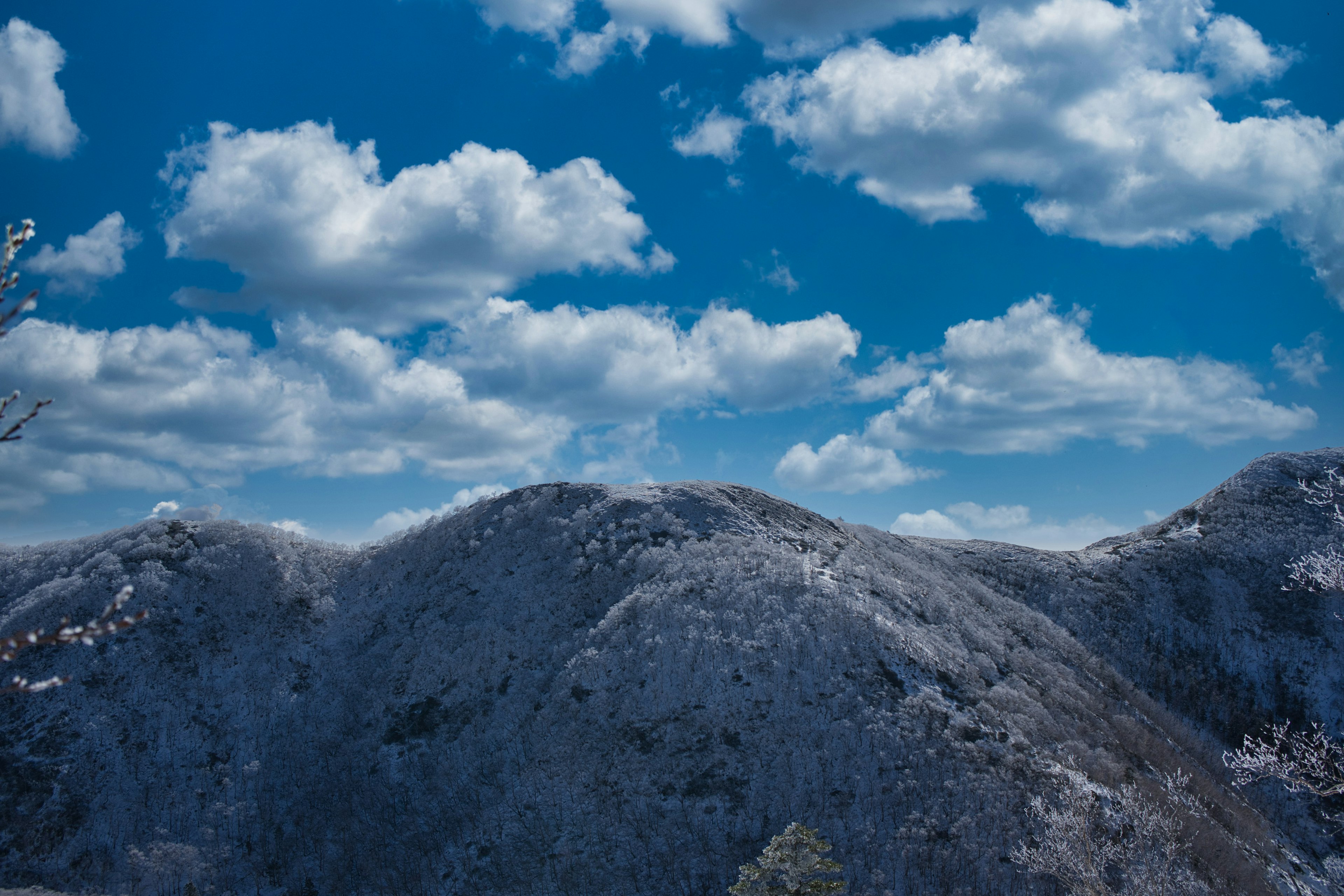 Montañas cubiertas de nieve bajo un cielo azul con nubes blancas y esponjosas