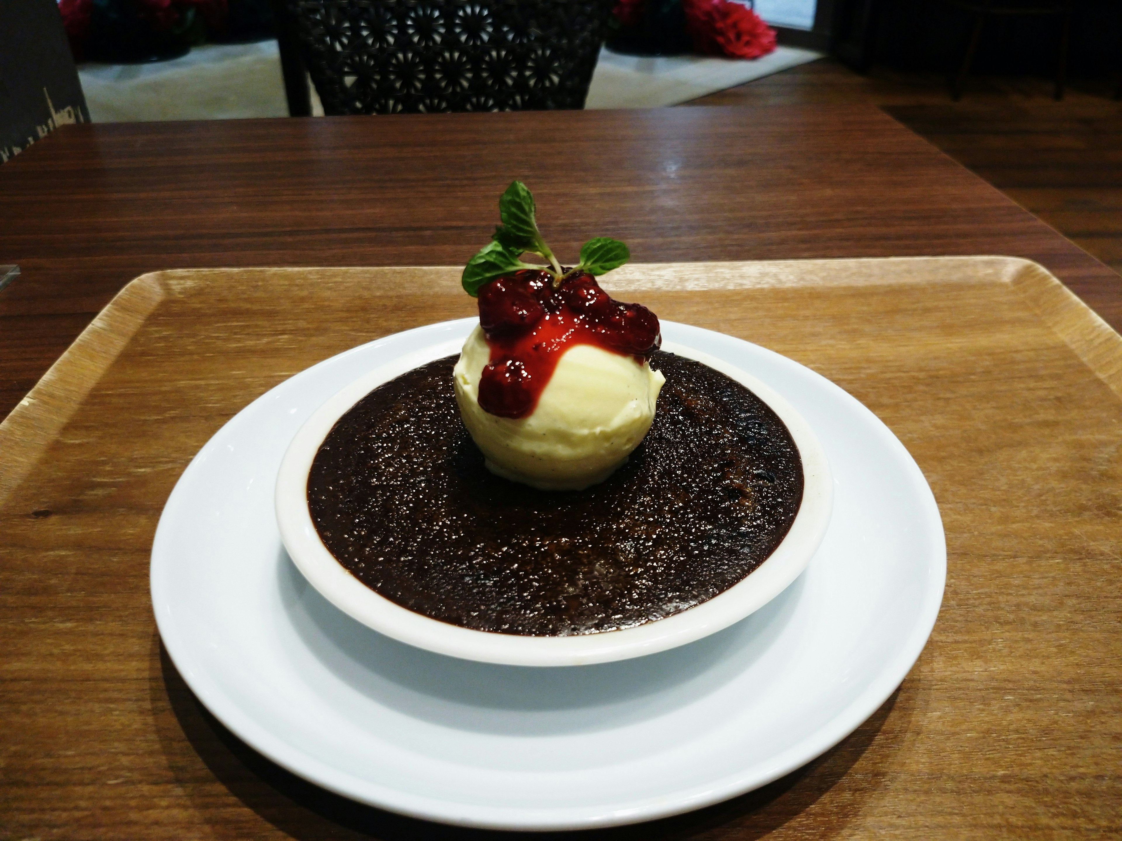 Postre con un cupcake cubierto de salsa de cereza y menta sobre una base de chocolate