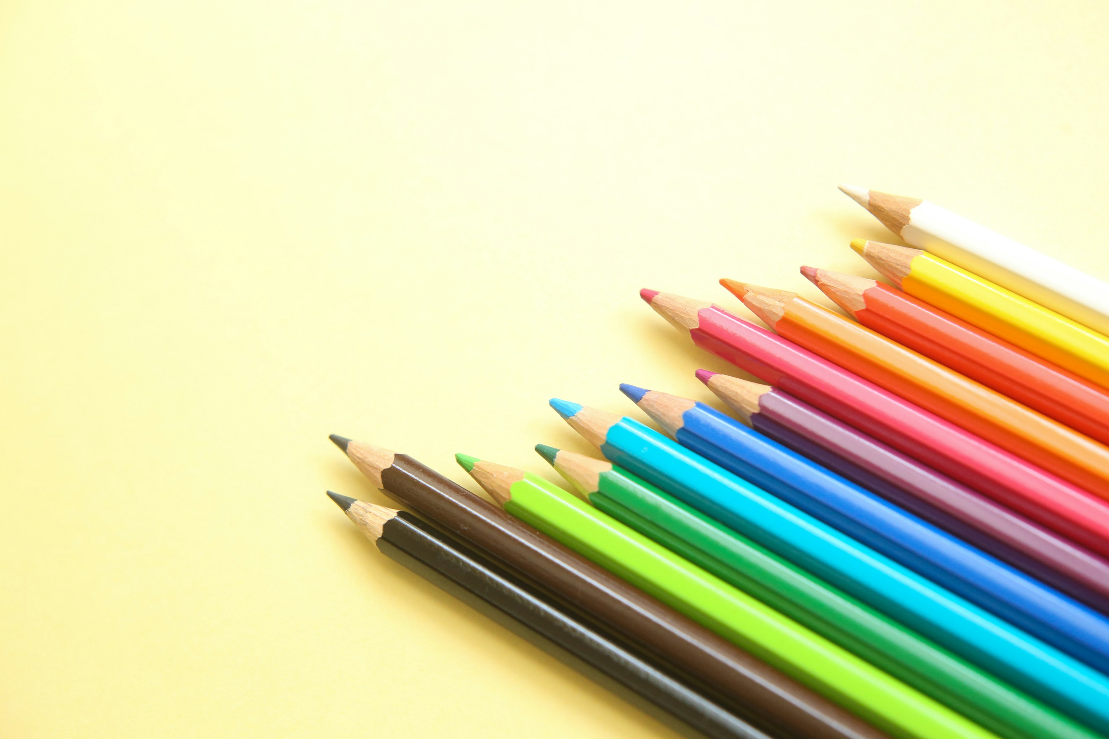 Colored pencils arranged on a yellow background