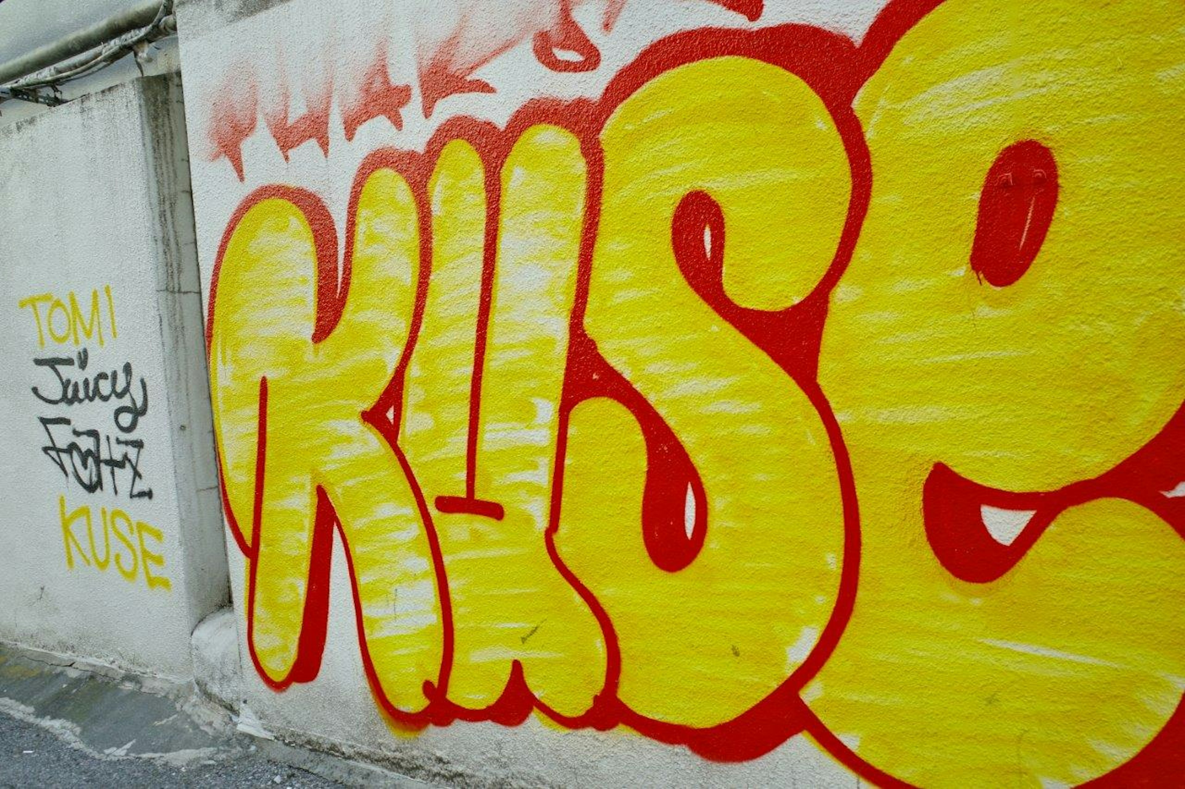 Bright yellow and red graffiti art on a wall featuring stylized letters