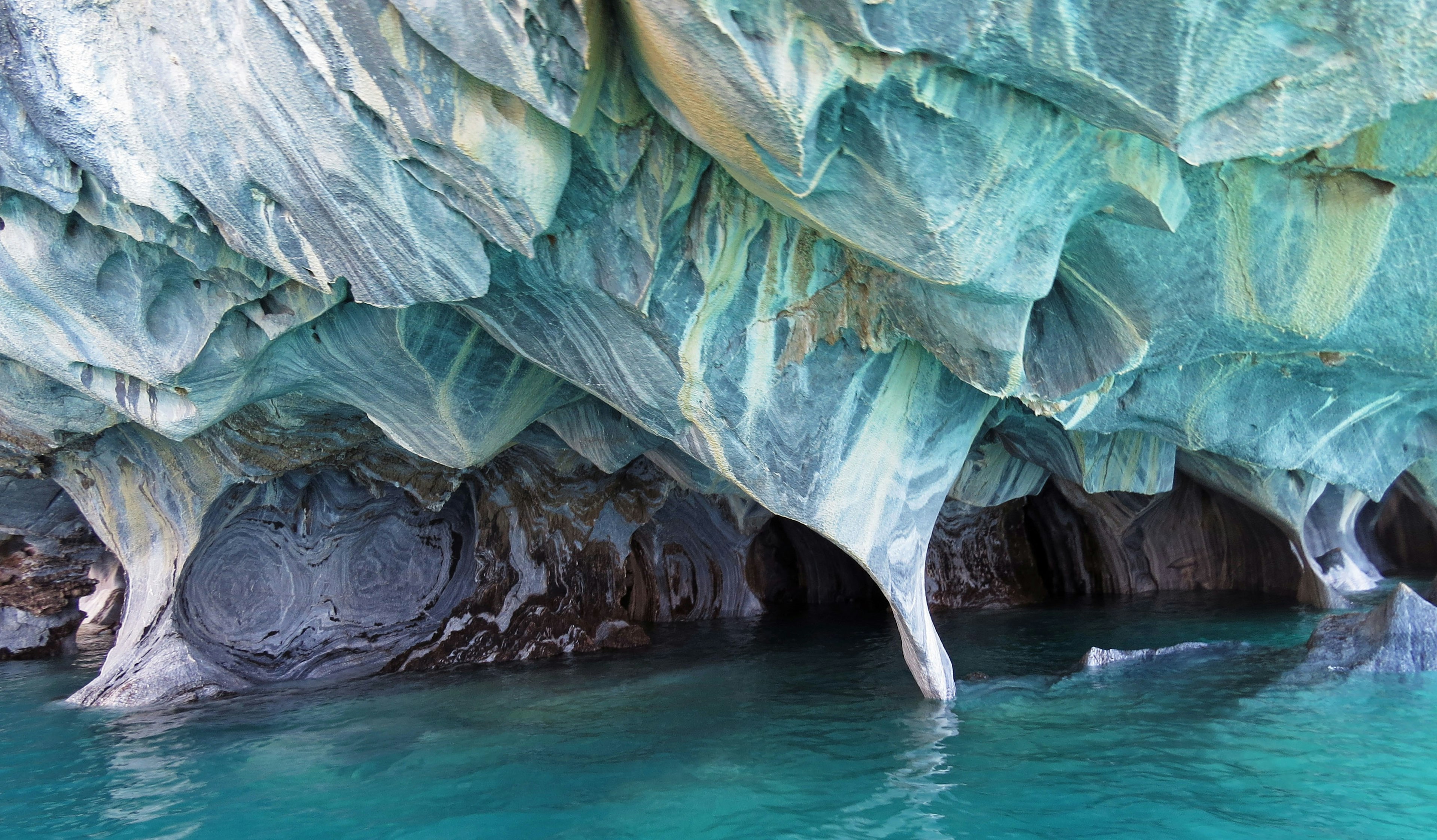 Unique shapes of marble caves surrounded by beautiful turquoise water