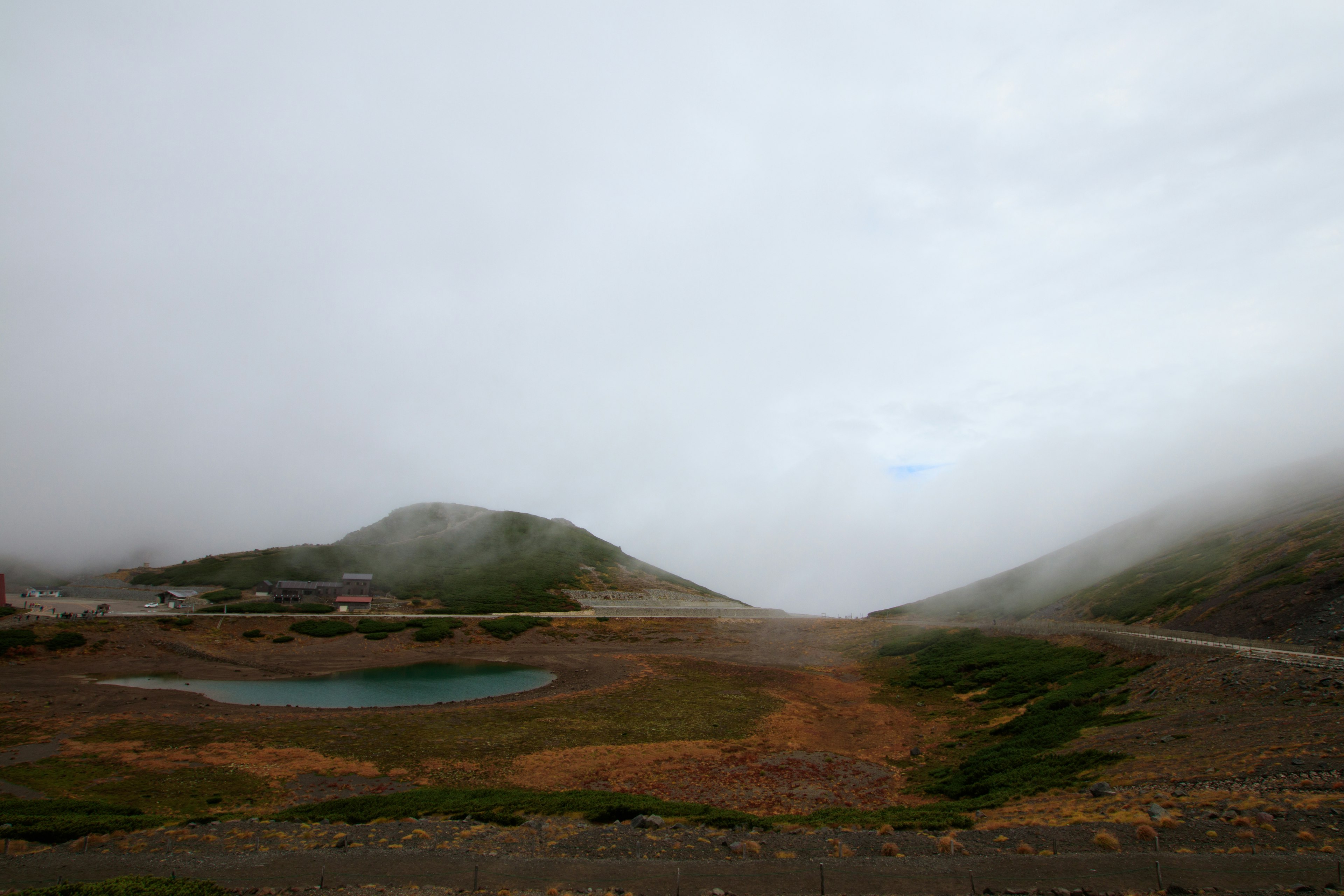 Fog-covered mountains with a small lake in the foreground