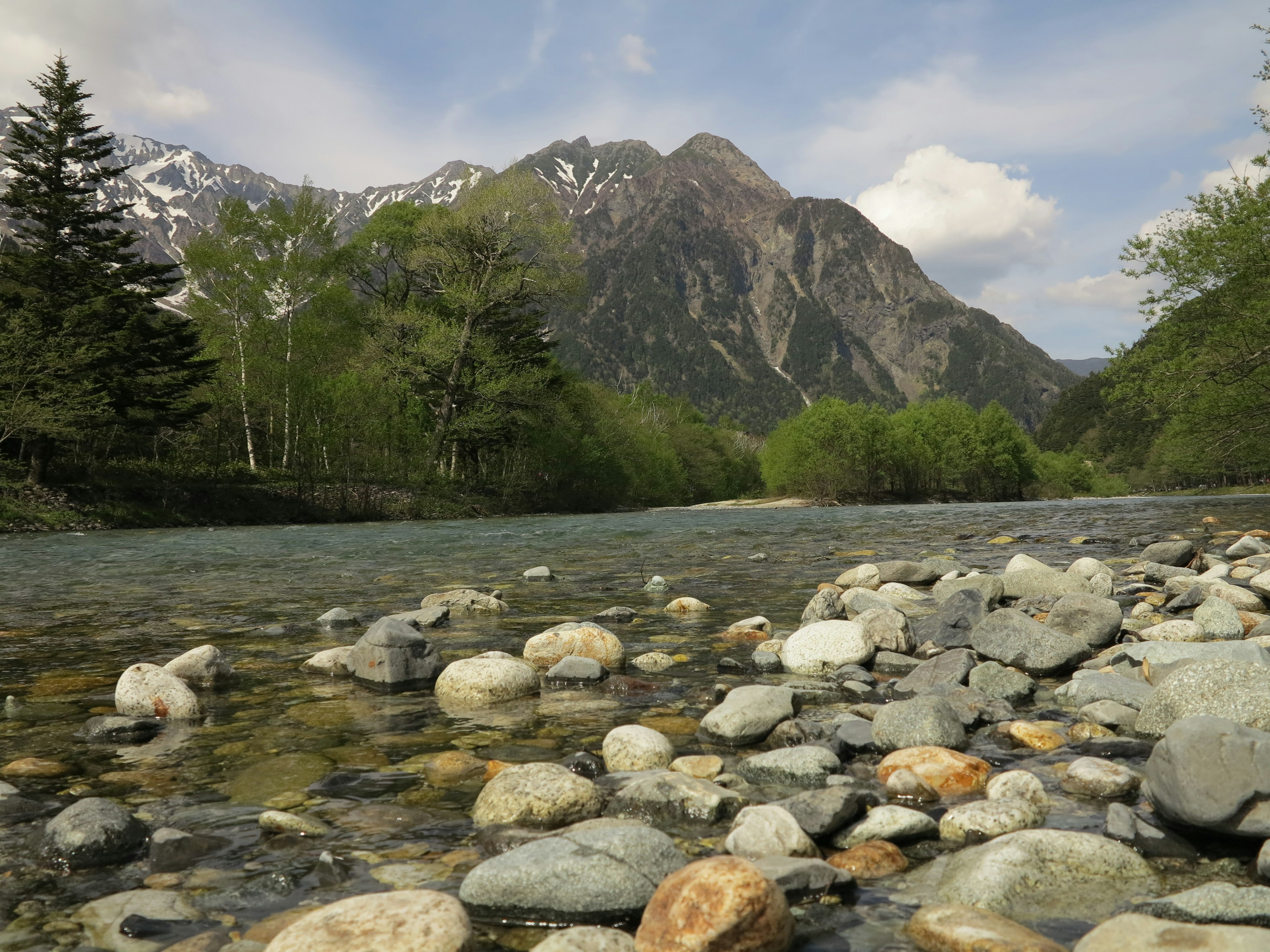 Pemandangan indah batu di tepi sungai dengan gunung di latar belakang