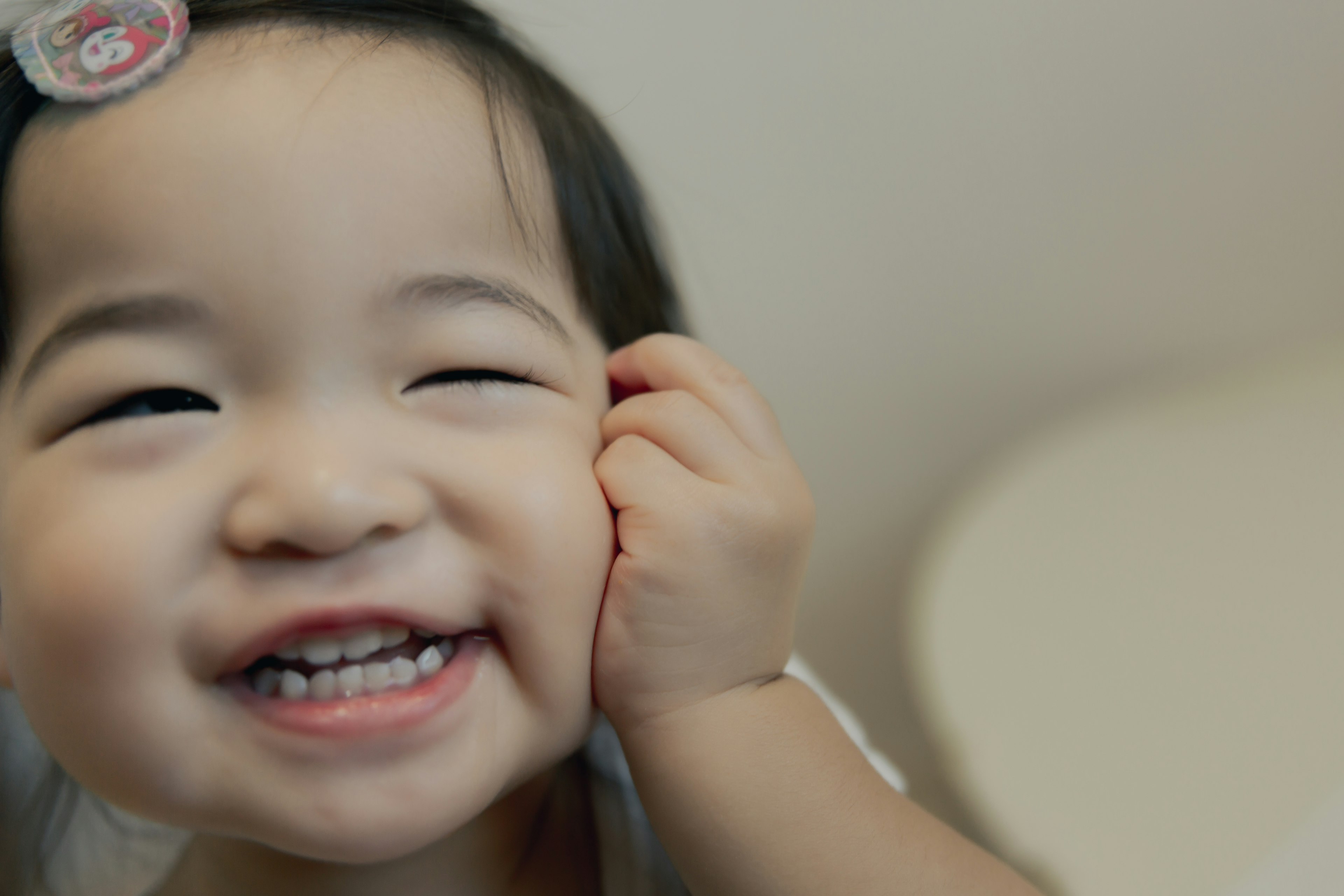 Enfant souriant pinçant sa joue avec sa main