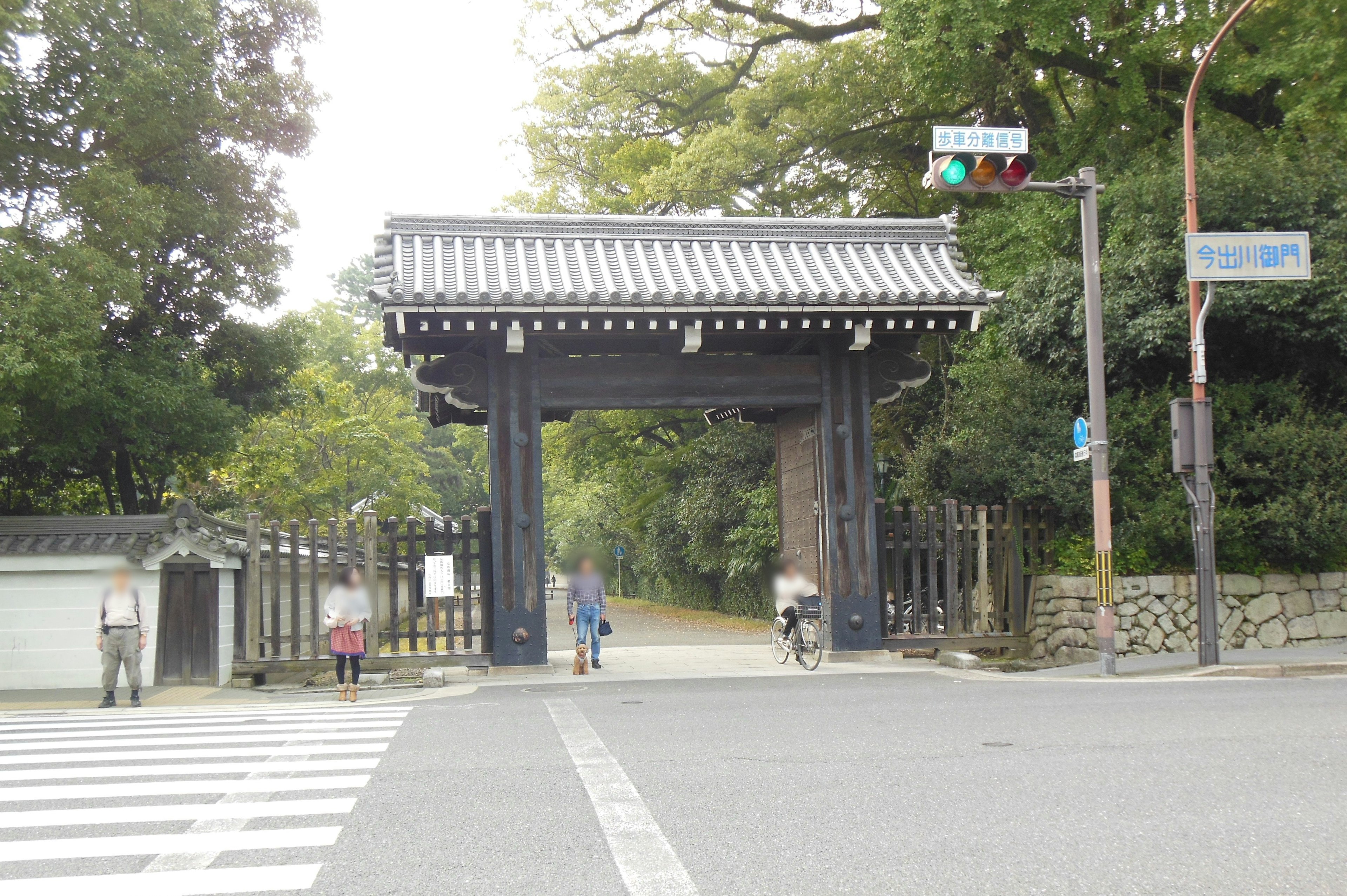 Historic gate with surrounding greenery and pedestrians