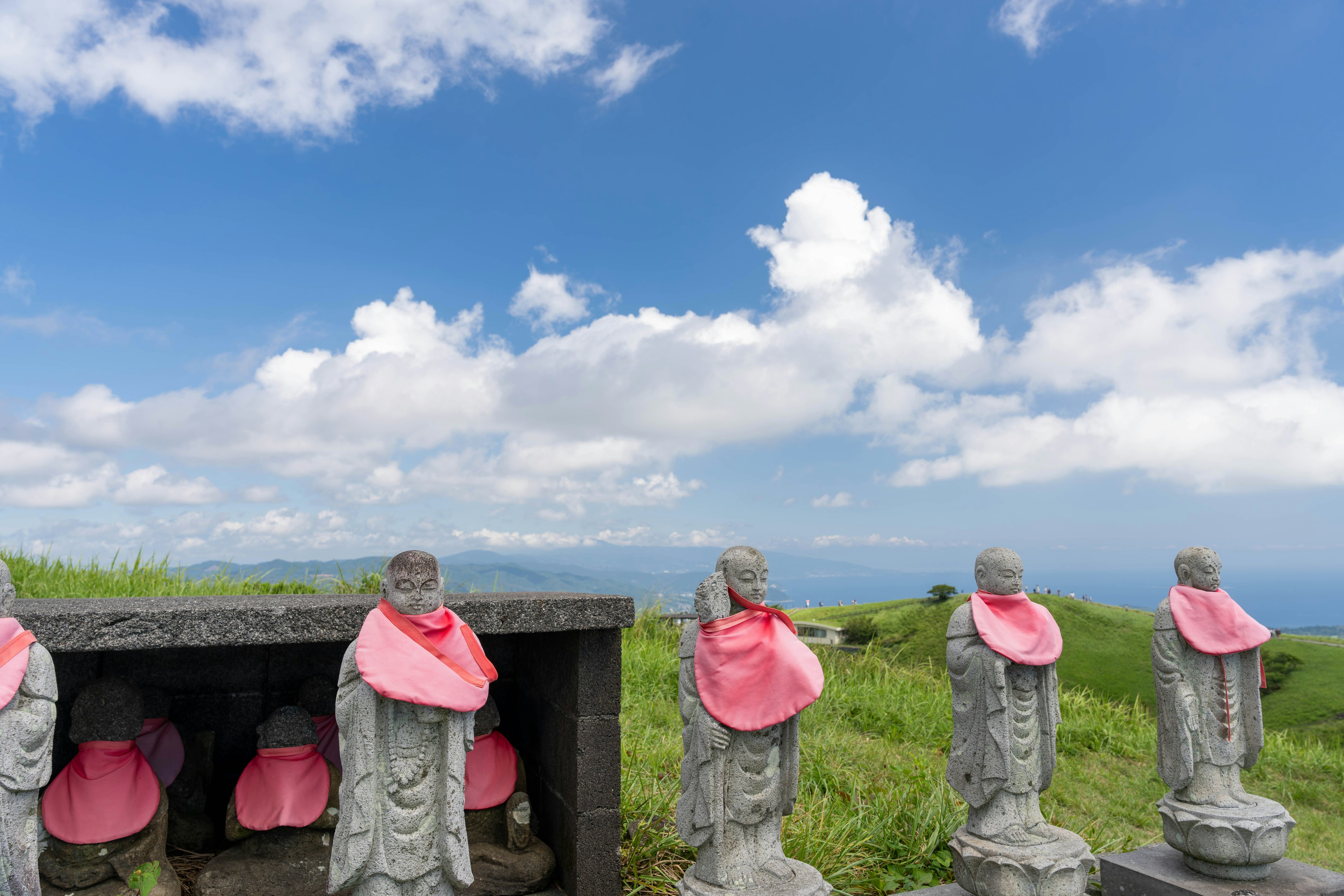 Stone statues wearing pink scarves under a blue sky