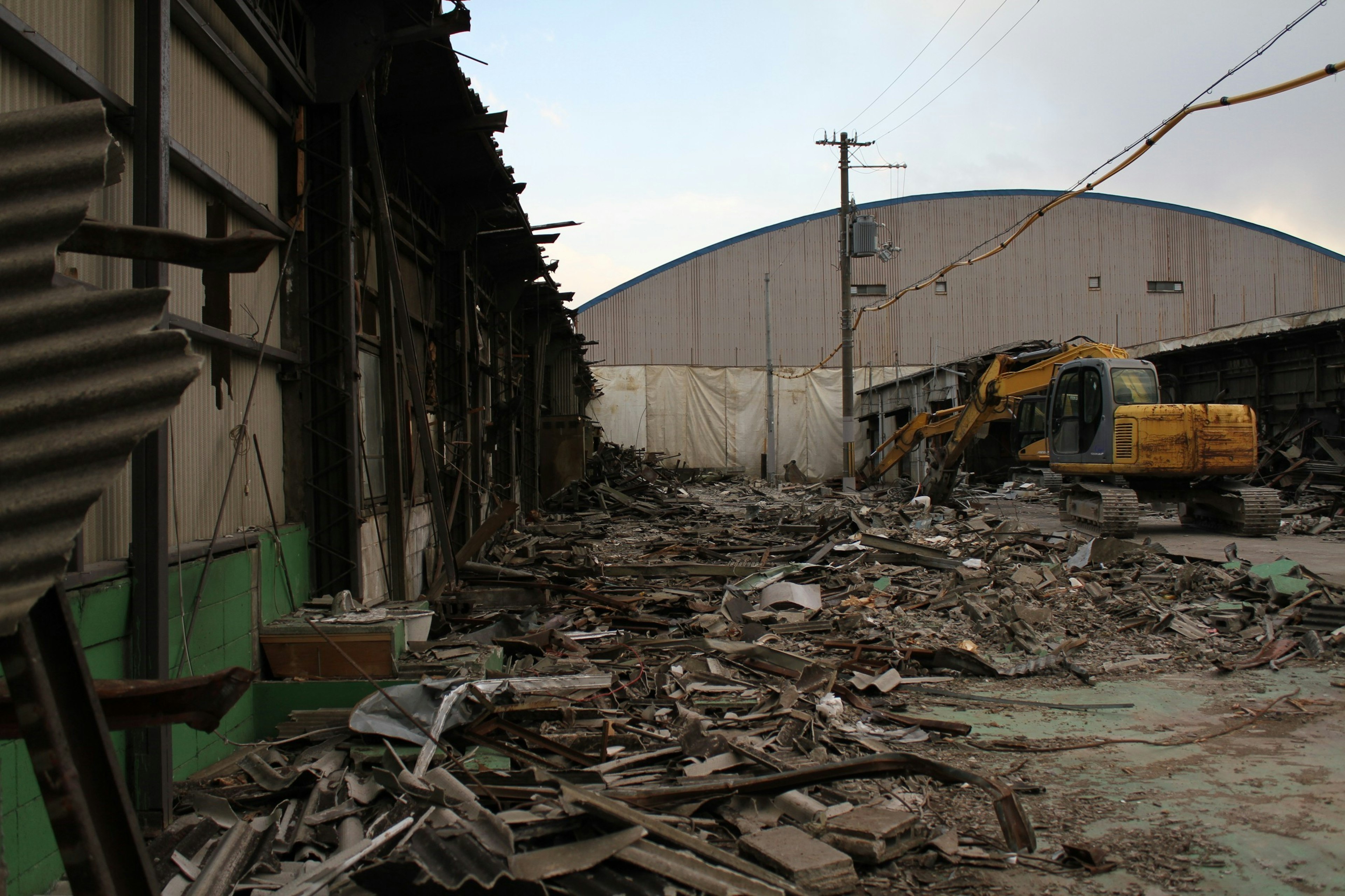 Zone d'usine abandonnée avec des débris éparpillés et des engins lourds