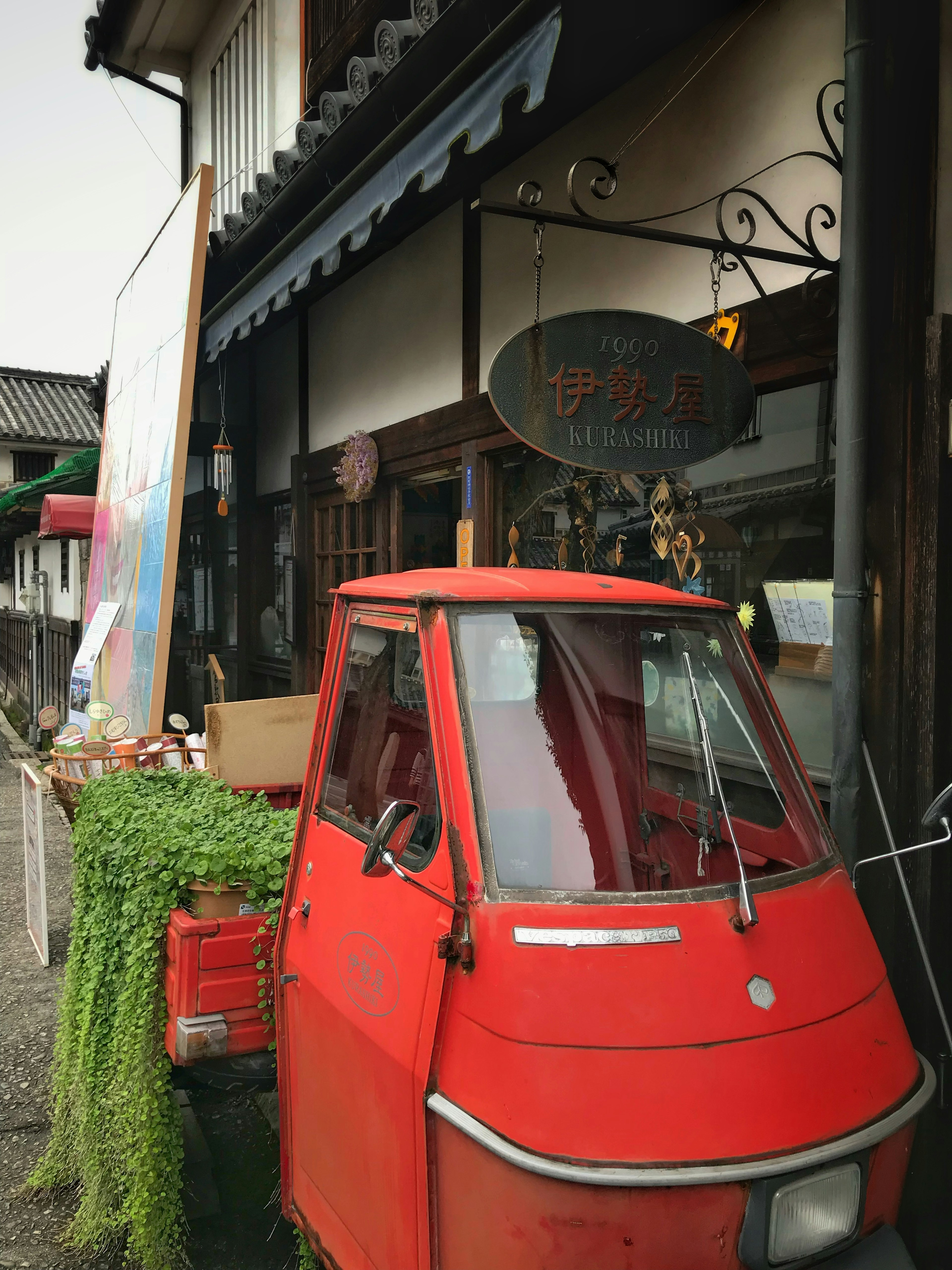 Red three-wheeled vehicle parked in front of a shop