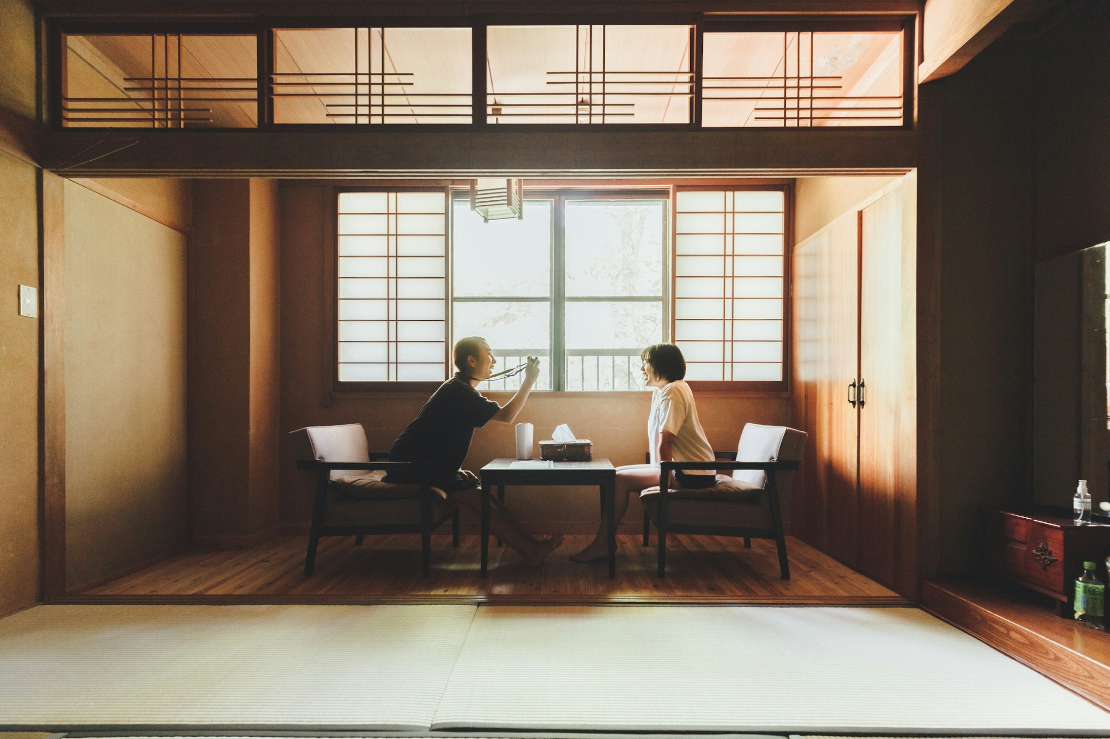 Two people sitting in a traditional Japanese room with natural light coming through the window