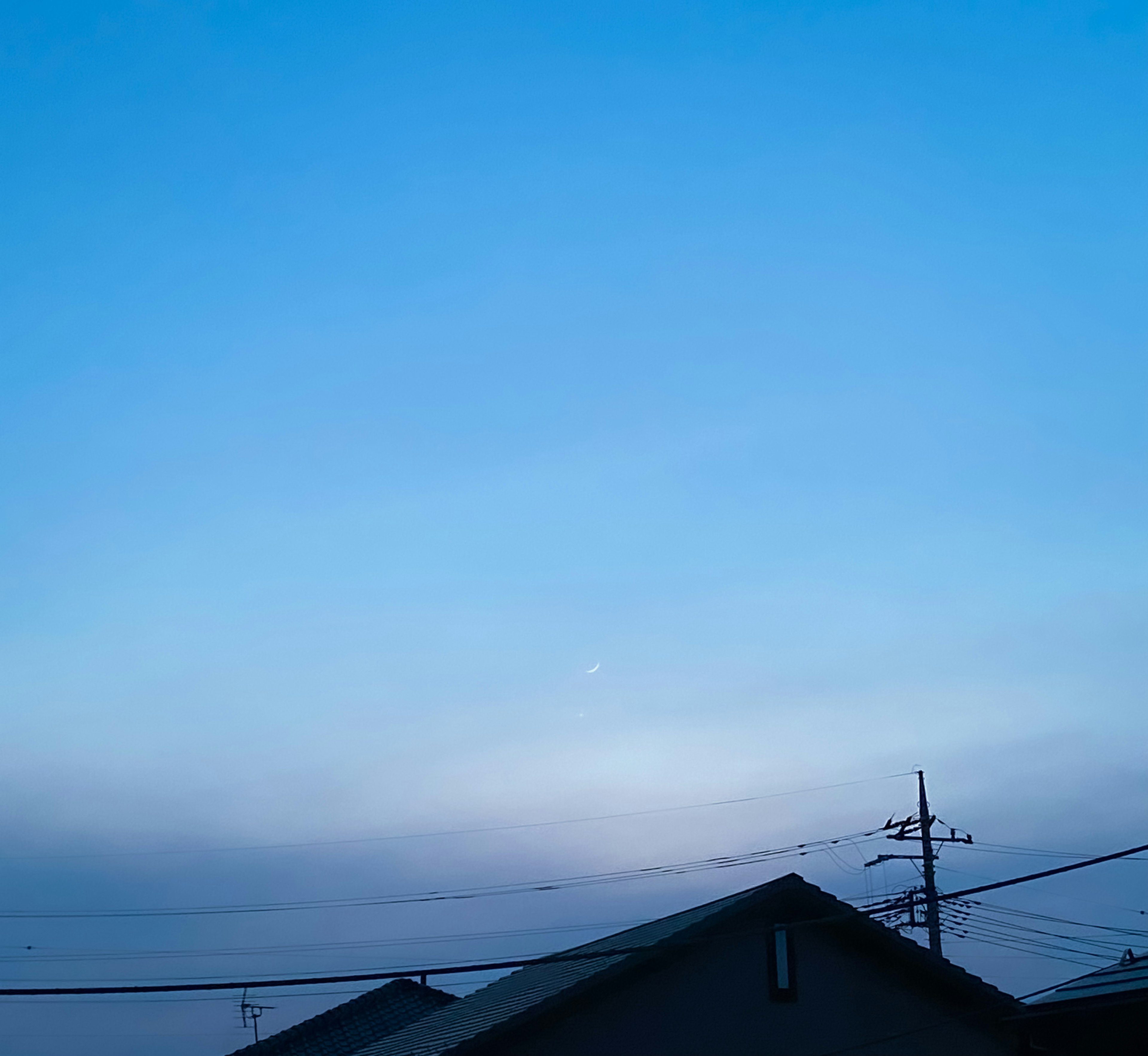 Langit biru yang tenang dengan awan lembut di atas atap