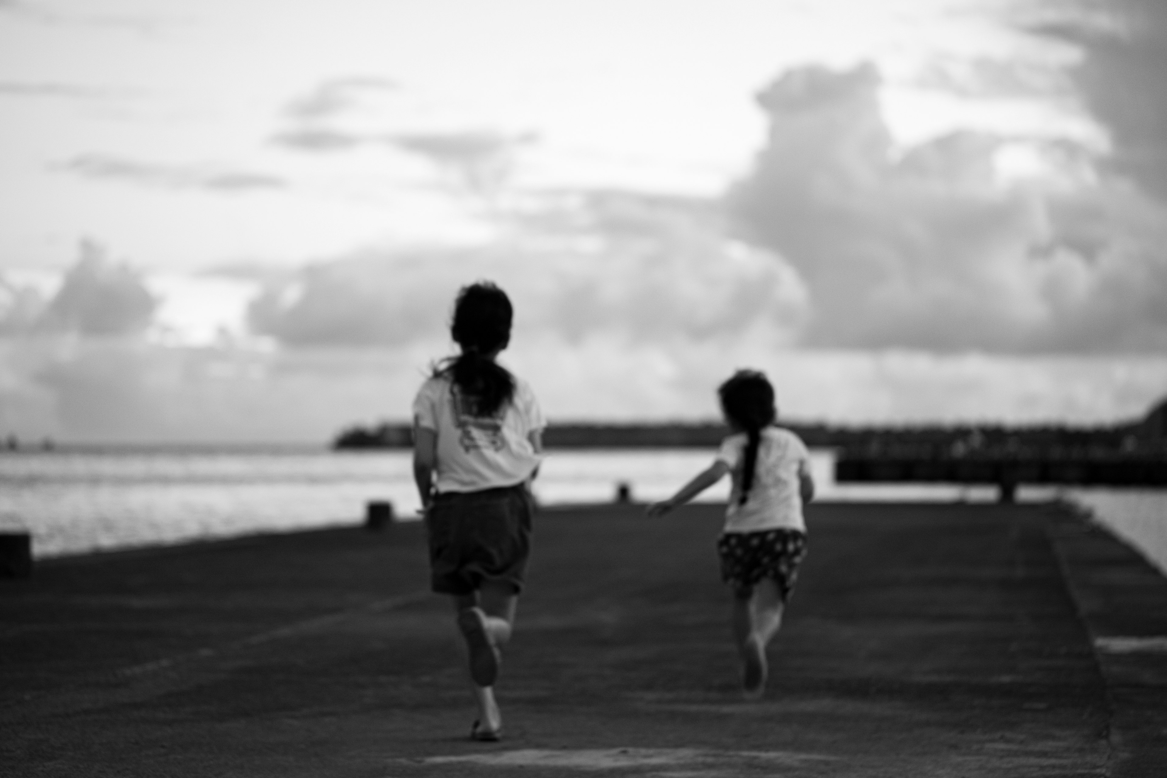 Black and white photo of children running towards the sea