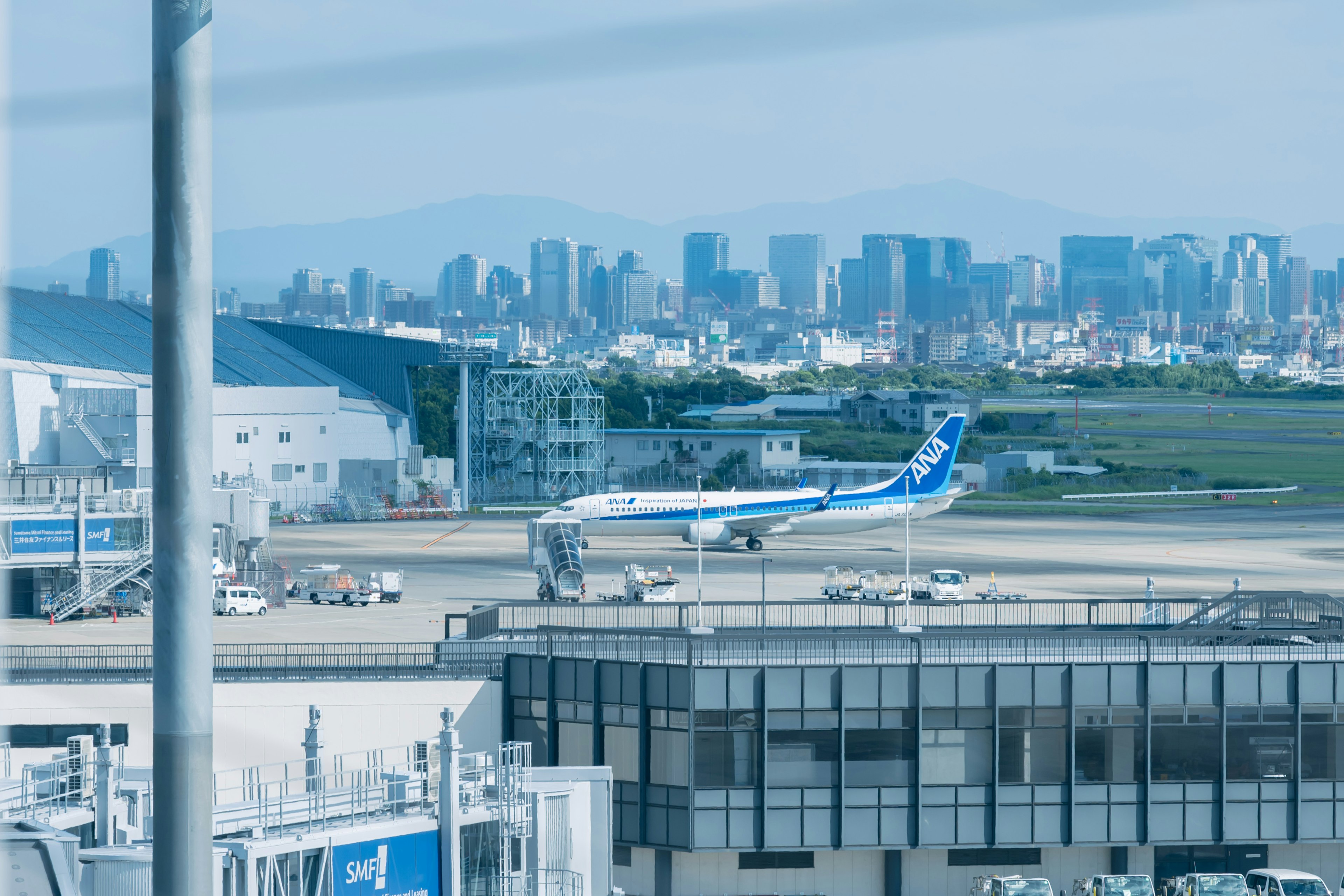 Avion de passagers bleu sur la piste de l'aéroport avec la ligne d'horizon de la ville en arrière-plan