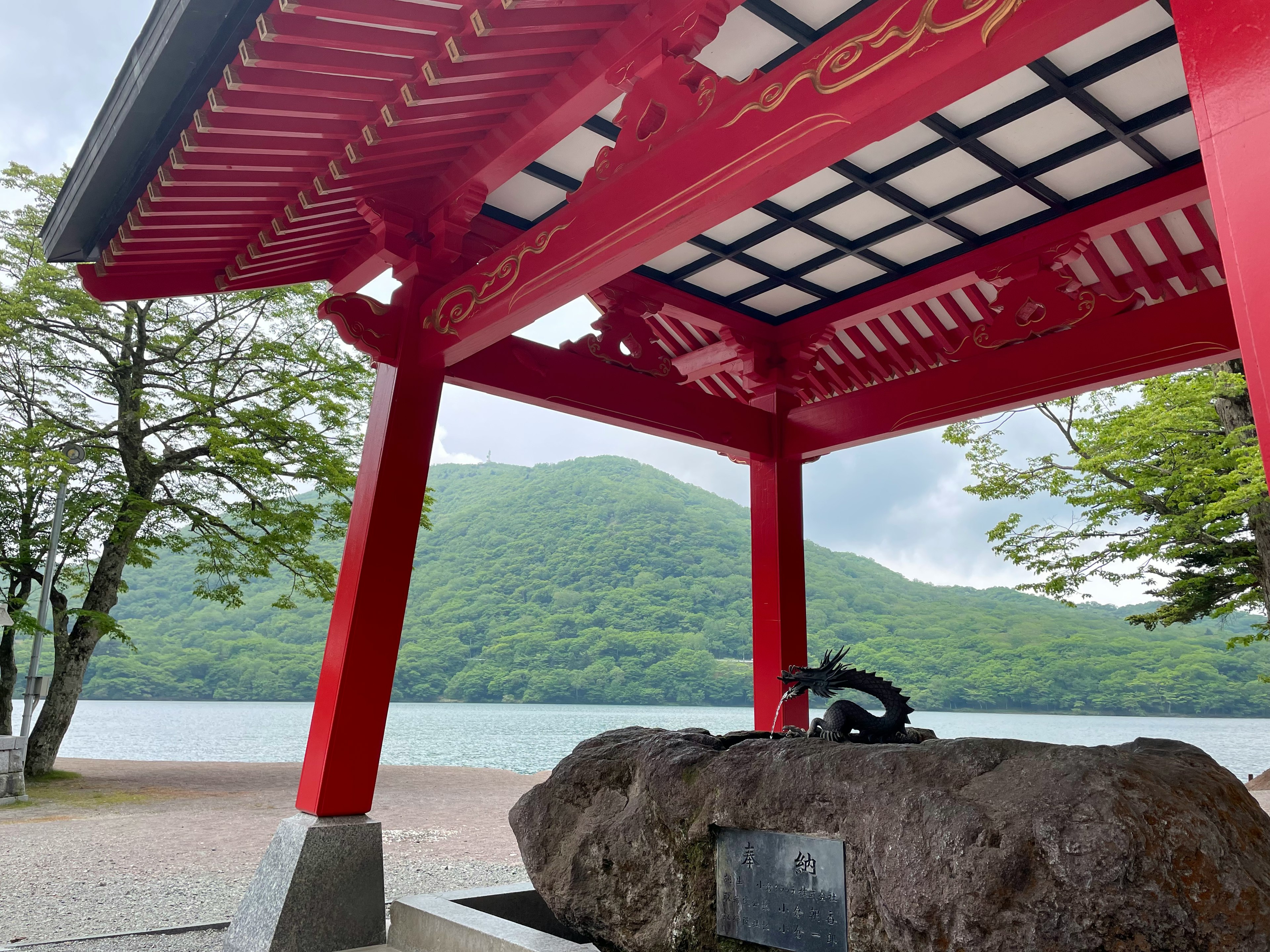 赤い屋根の下にある石の水槽と緑の山の背景