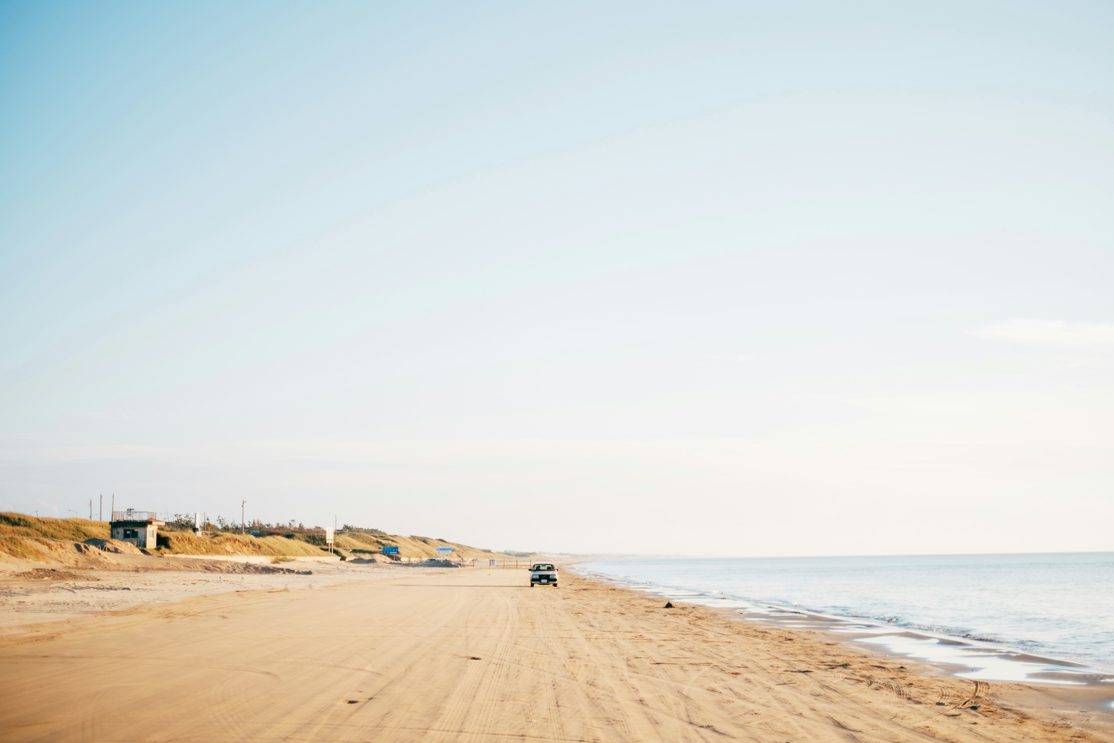 Plage de sable expansive avec mer calme une voiture roulant sur la route