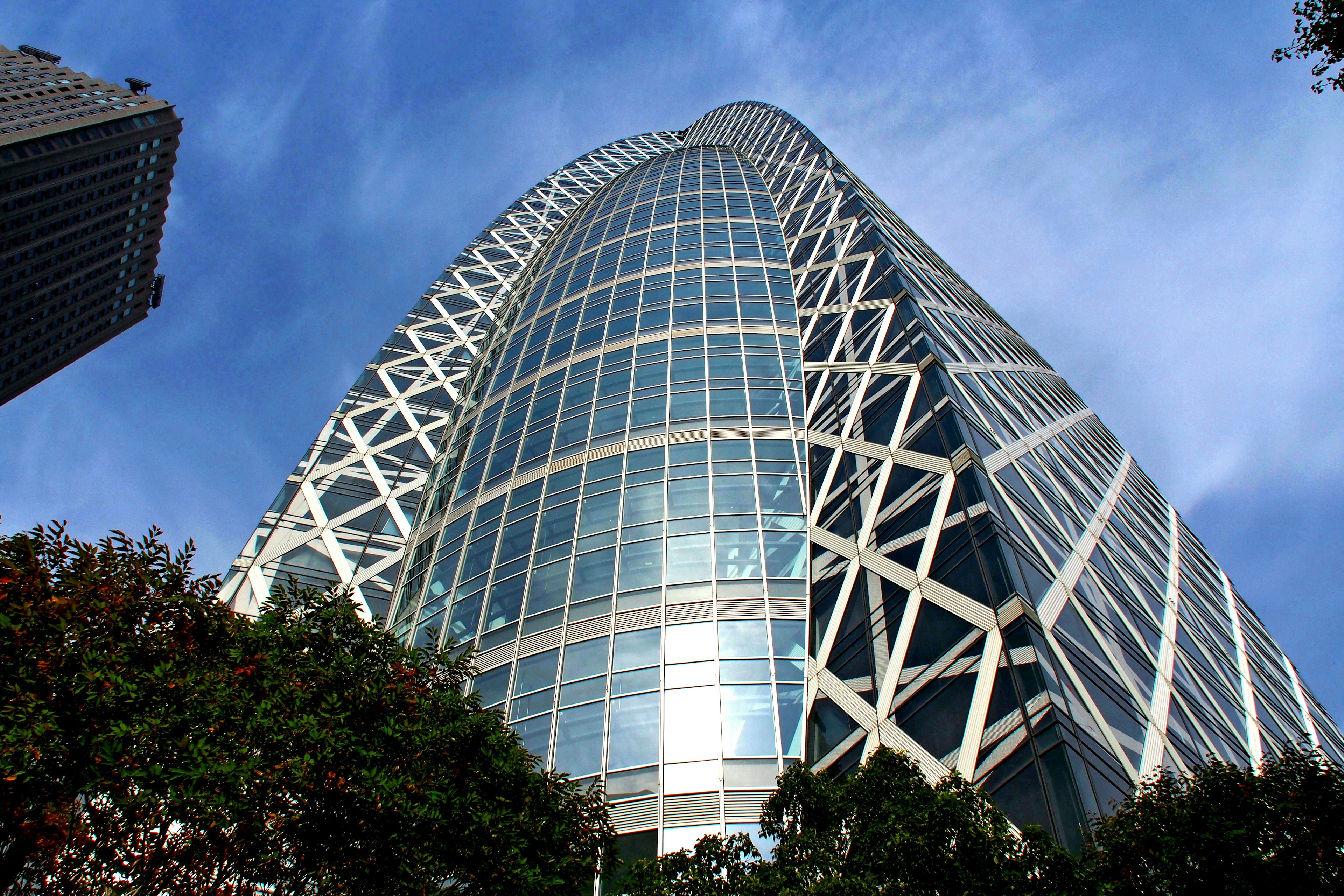 A photo taken from below of a skyscraper showcasing its glass and metal structure