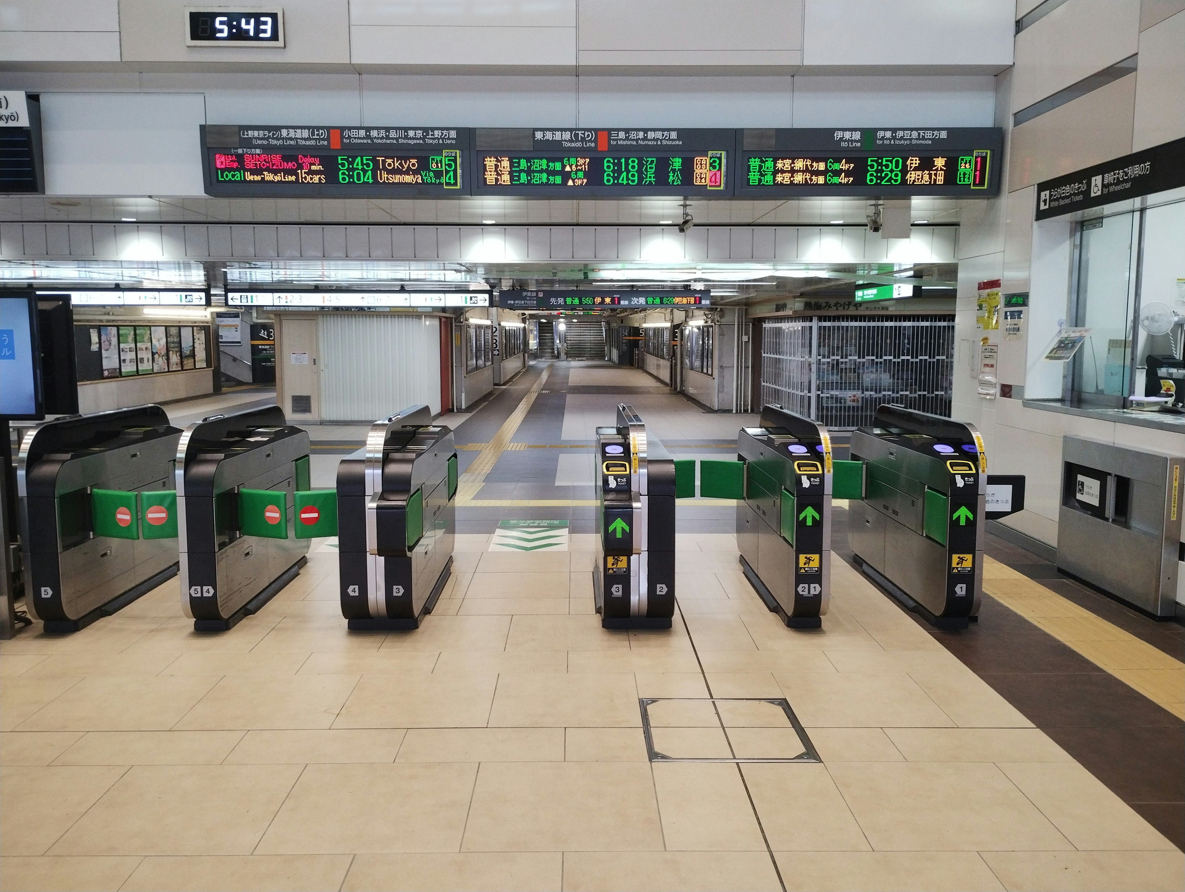 Spacious train station entrance with ticket gates and digital display boards