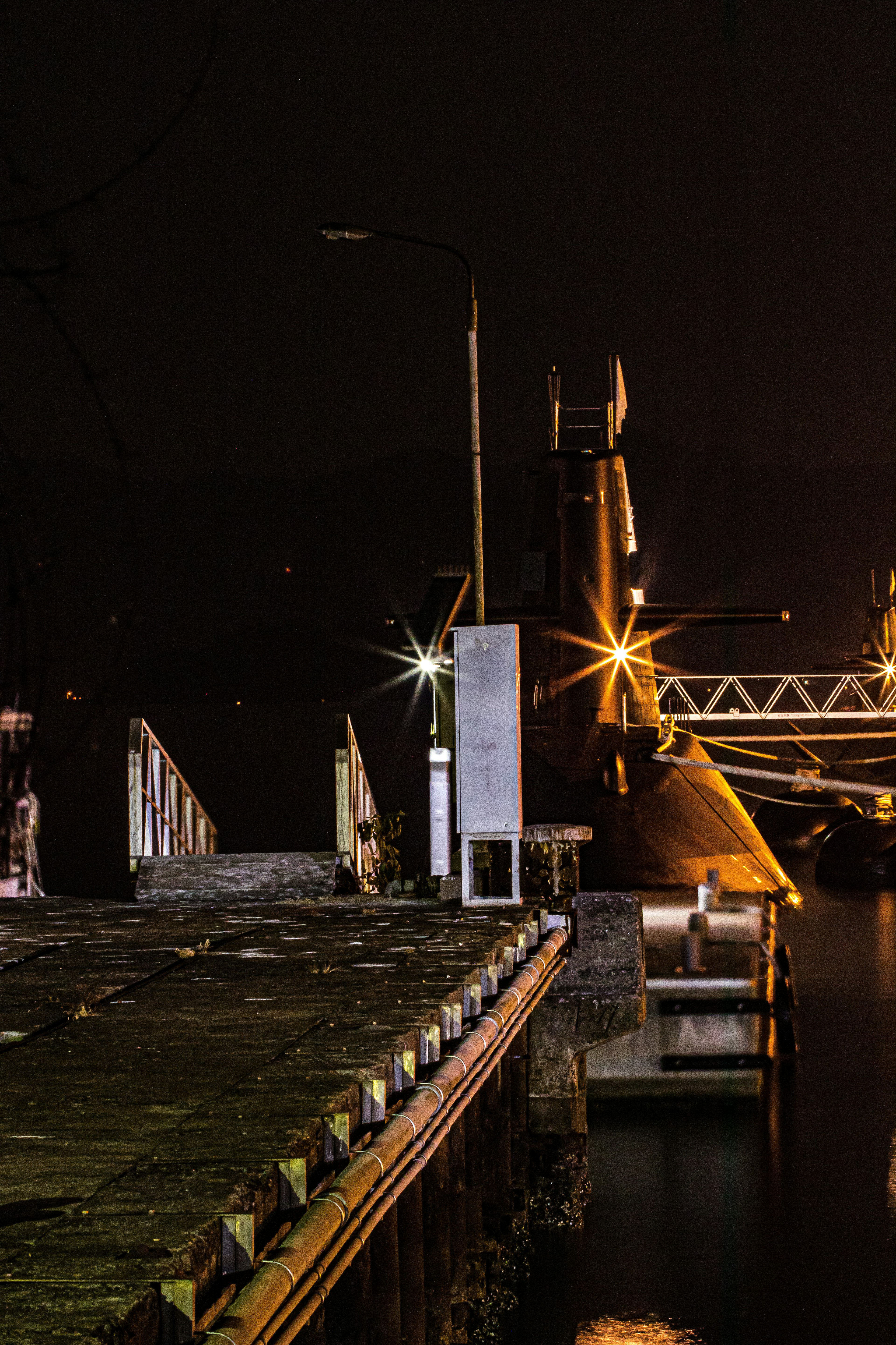 A ship docked at a harbor at night with bright lighting