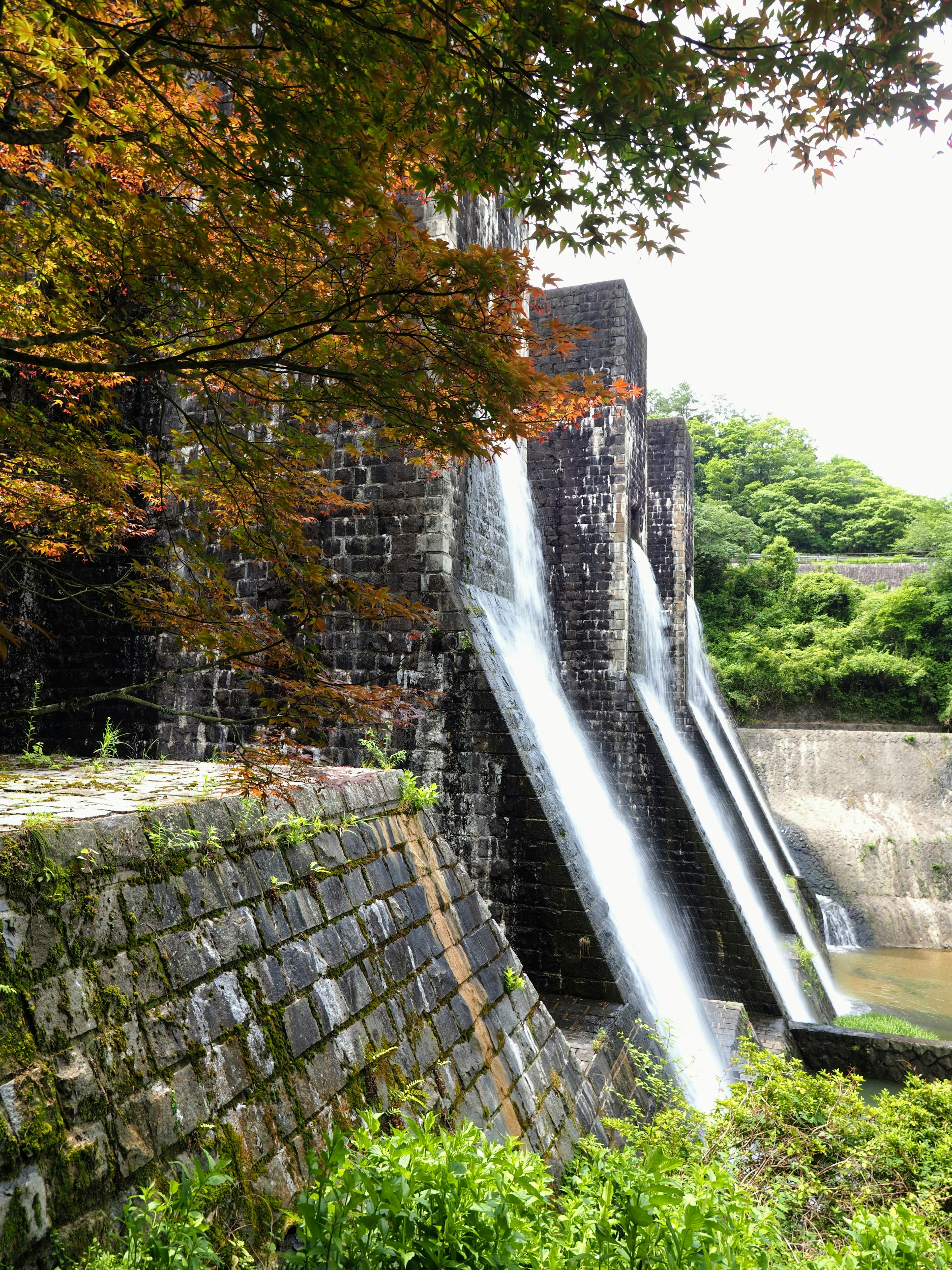 Barrage en pierre avec des chutes d'eau et une verdure environnante