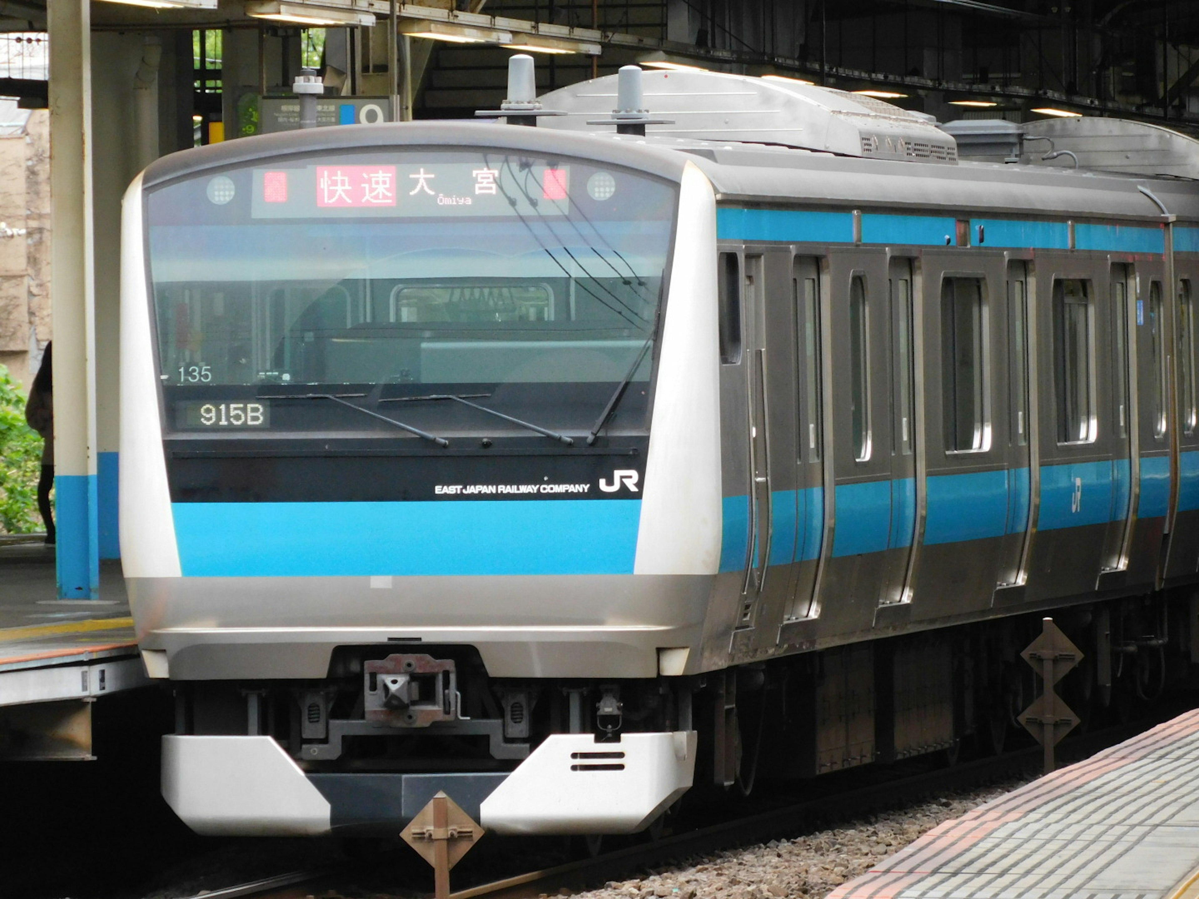 青と銀のデザインの日本のJR電車が駅に停車中