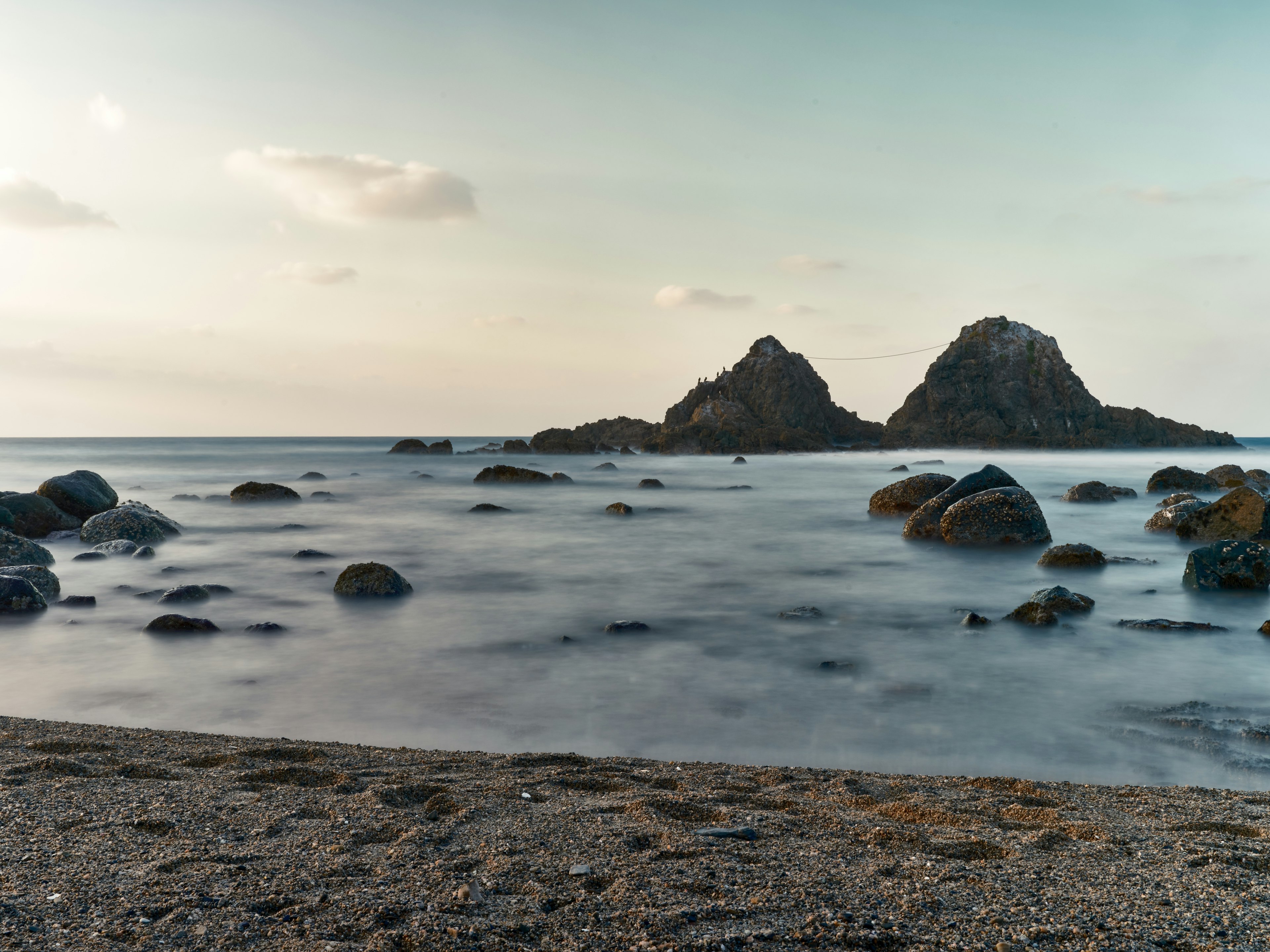 Pemandangan pantai terpencil dengan dua bukit berbatu di kejauhan