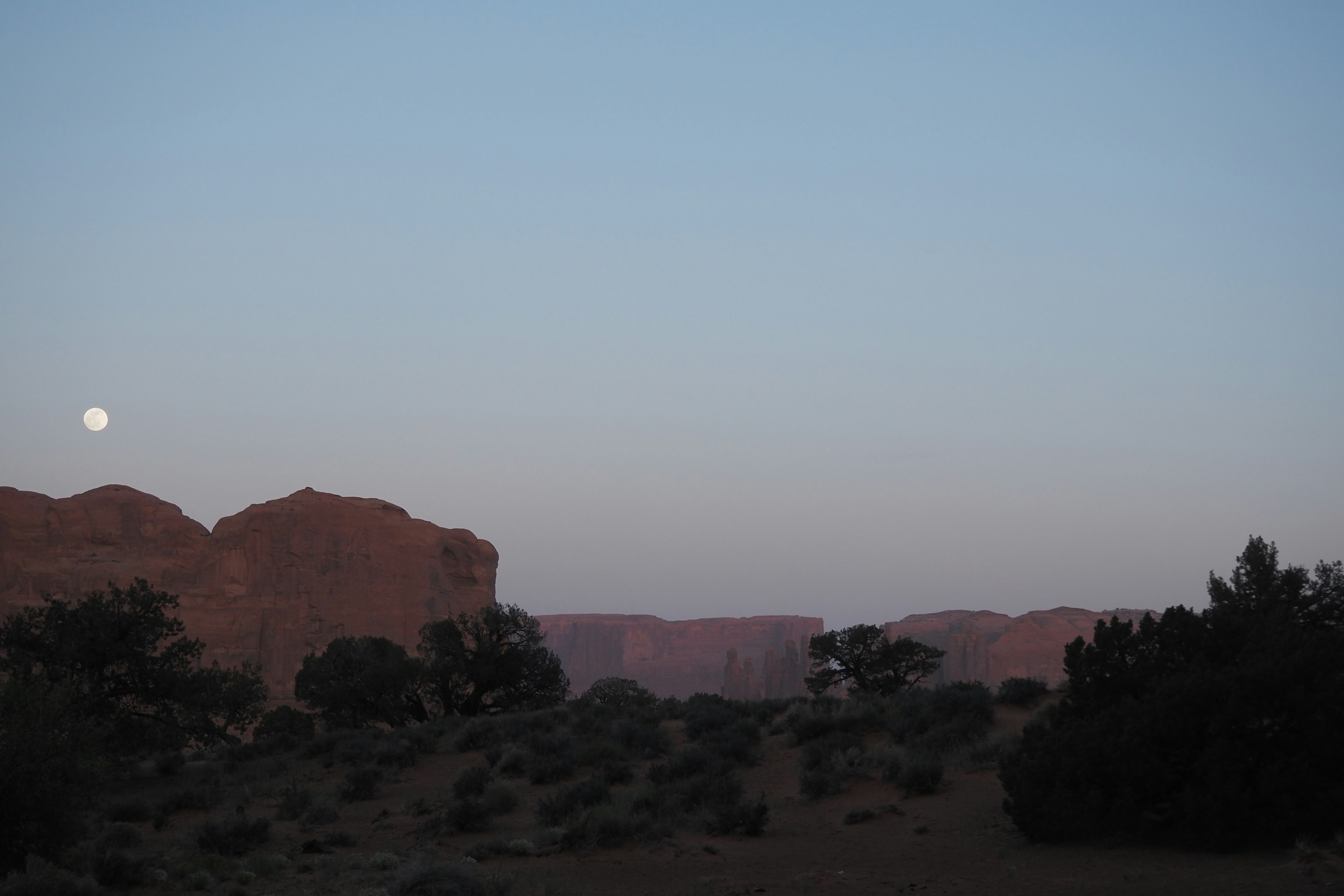 Ruhige Wüstenlandschaft in der Dämmerung mit dem Mond am Himmel