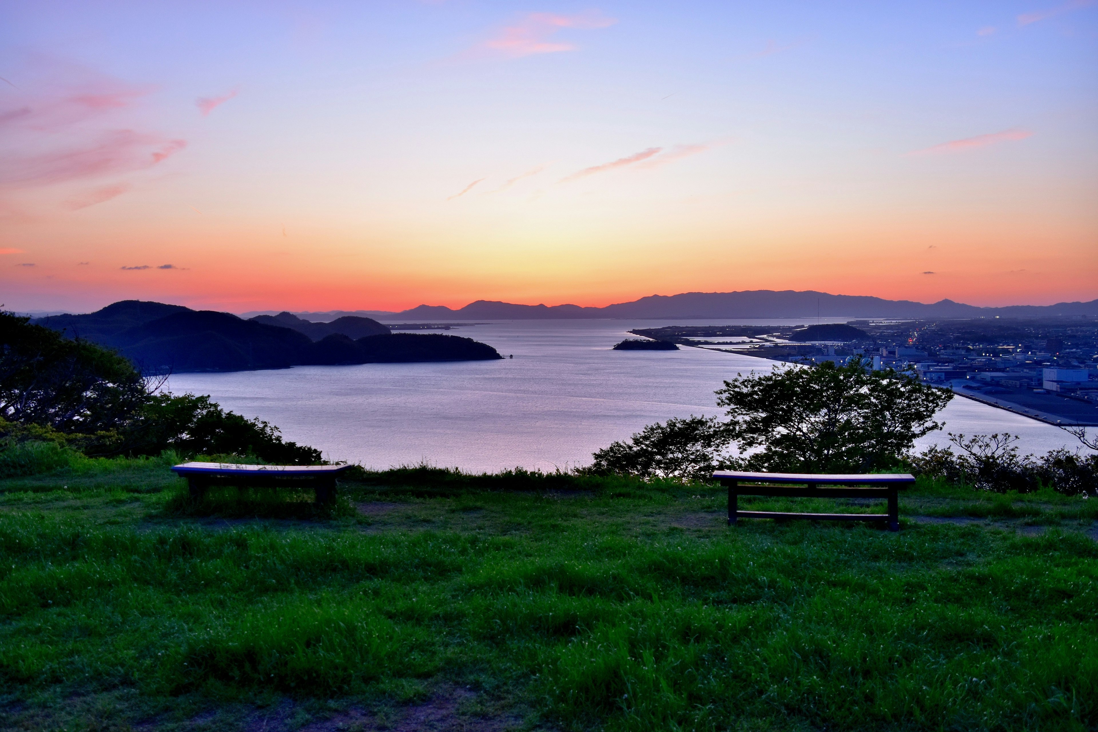 Vue pittoresque du coucher de soleil sur la mer avec des bancs dans une zone herbeuse