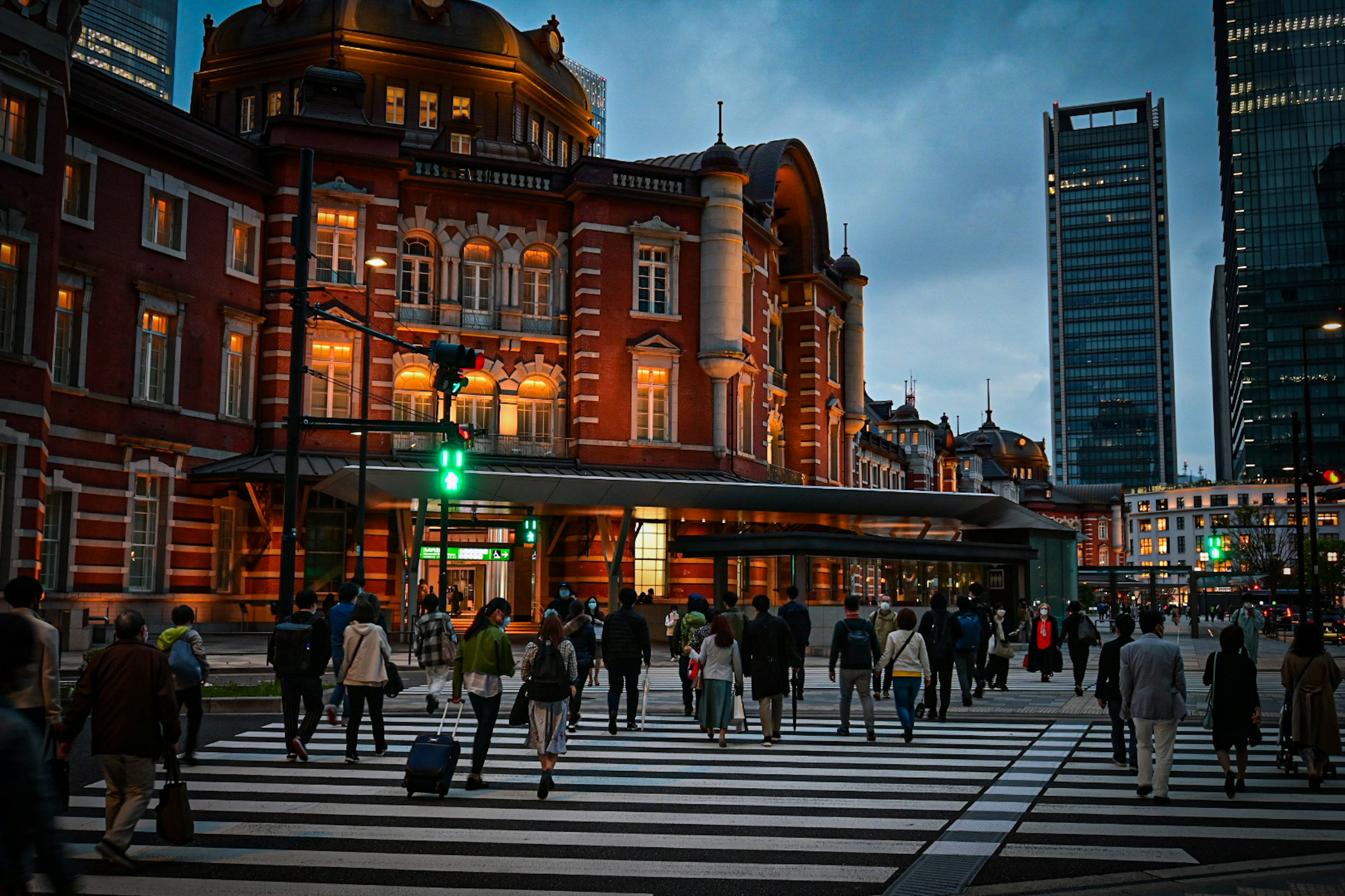 Estación de Tokio de noche con peatones cruzando la calle