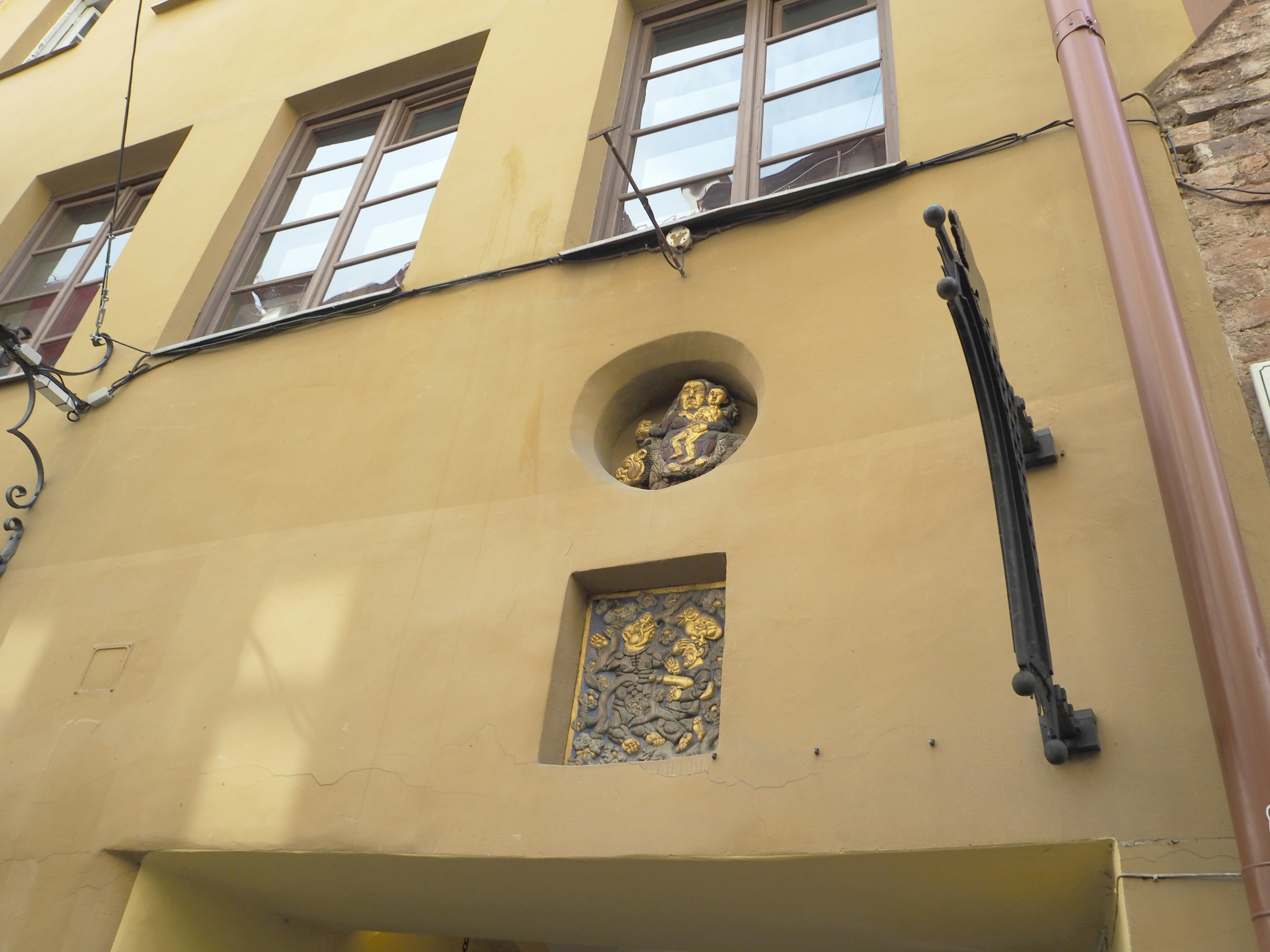 A yellow wall featuring a sculpture in a round niche and a rectangular window