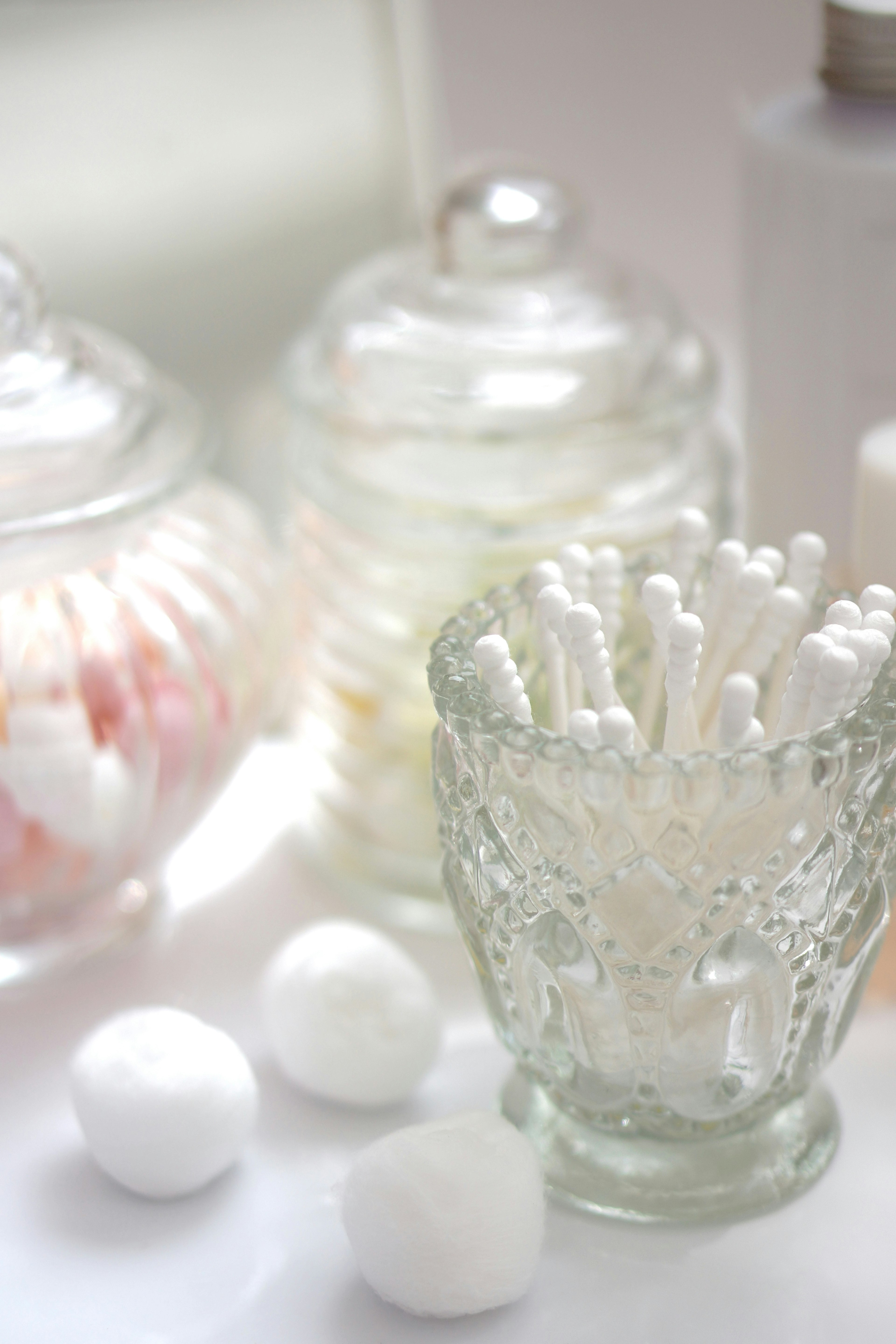 Still life image of cotton balls and cotton swabs in glass containers