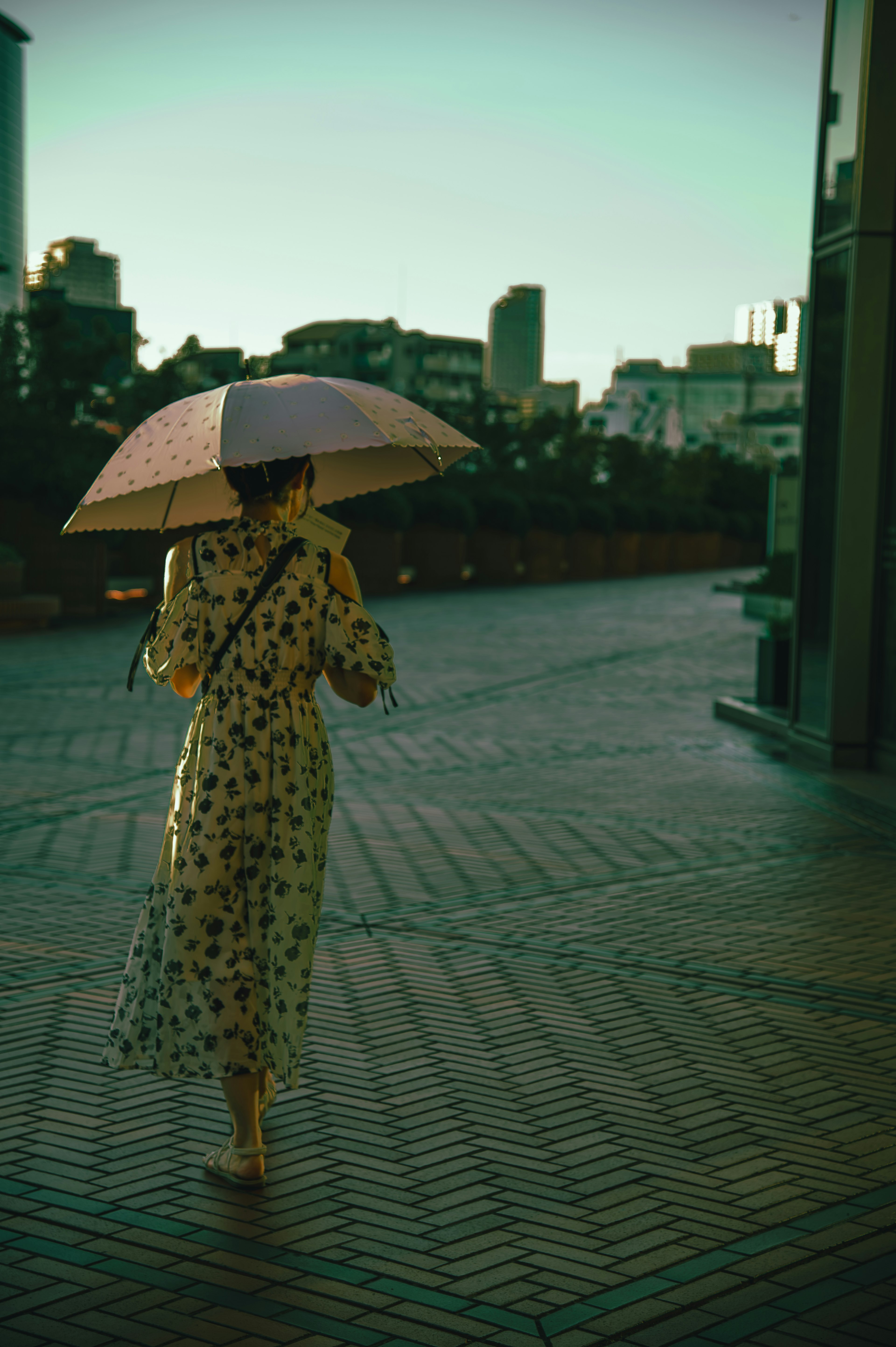 Une femme marchant avec un parapluie portant une robe jaune dans un cadre urbain