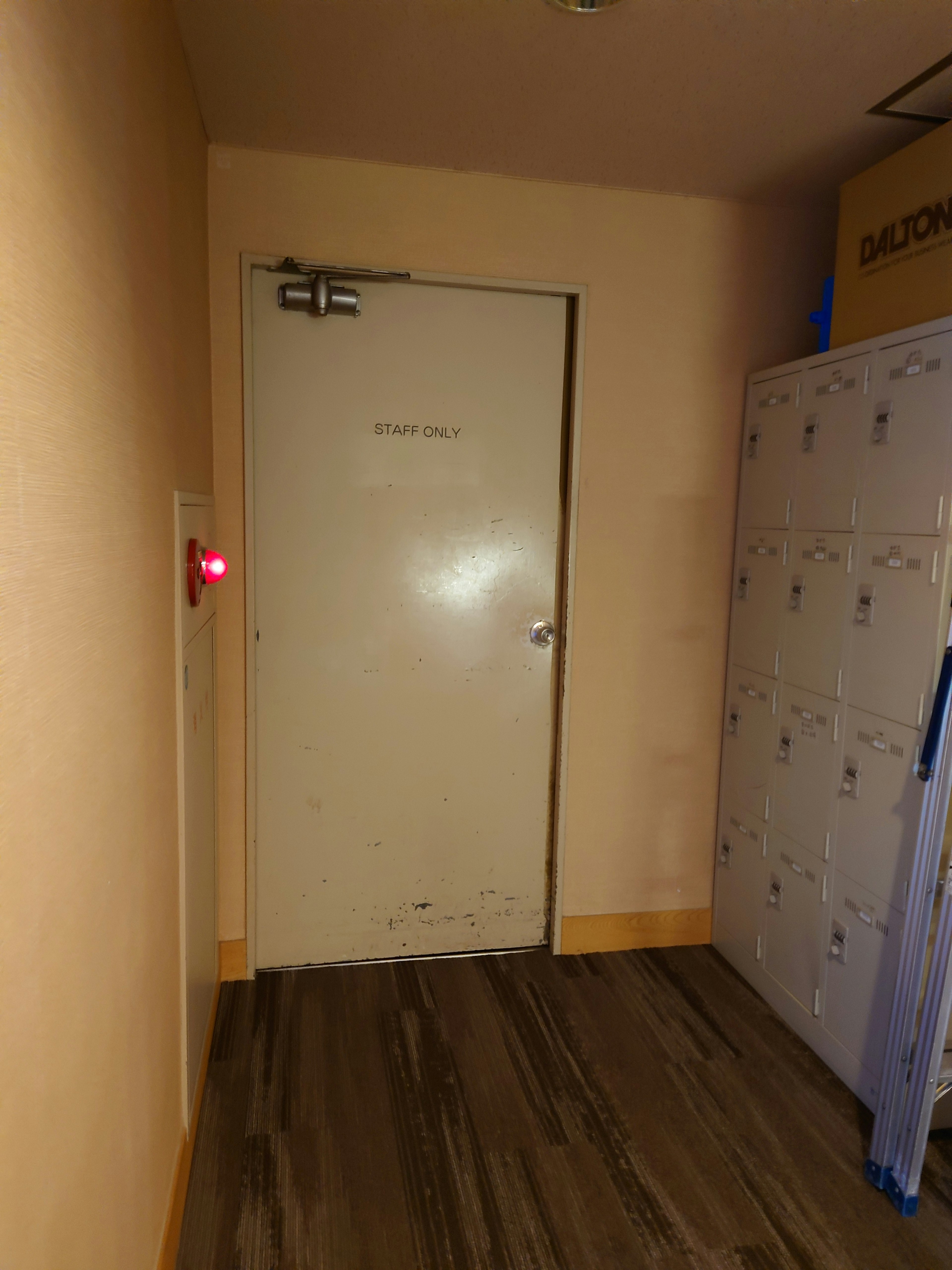 Image of a narrow hallway with a white door and lockers