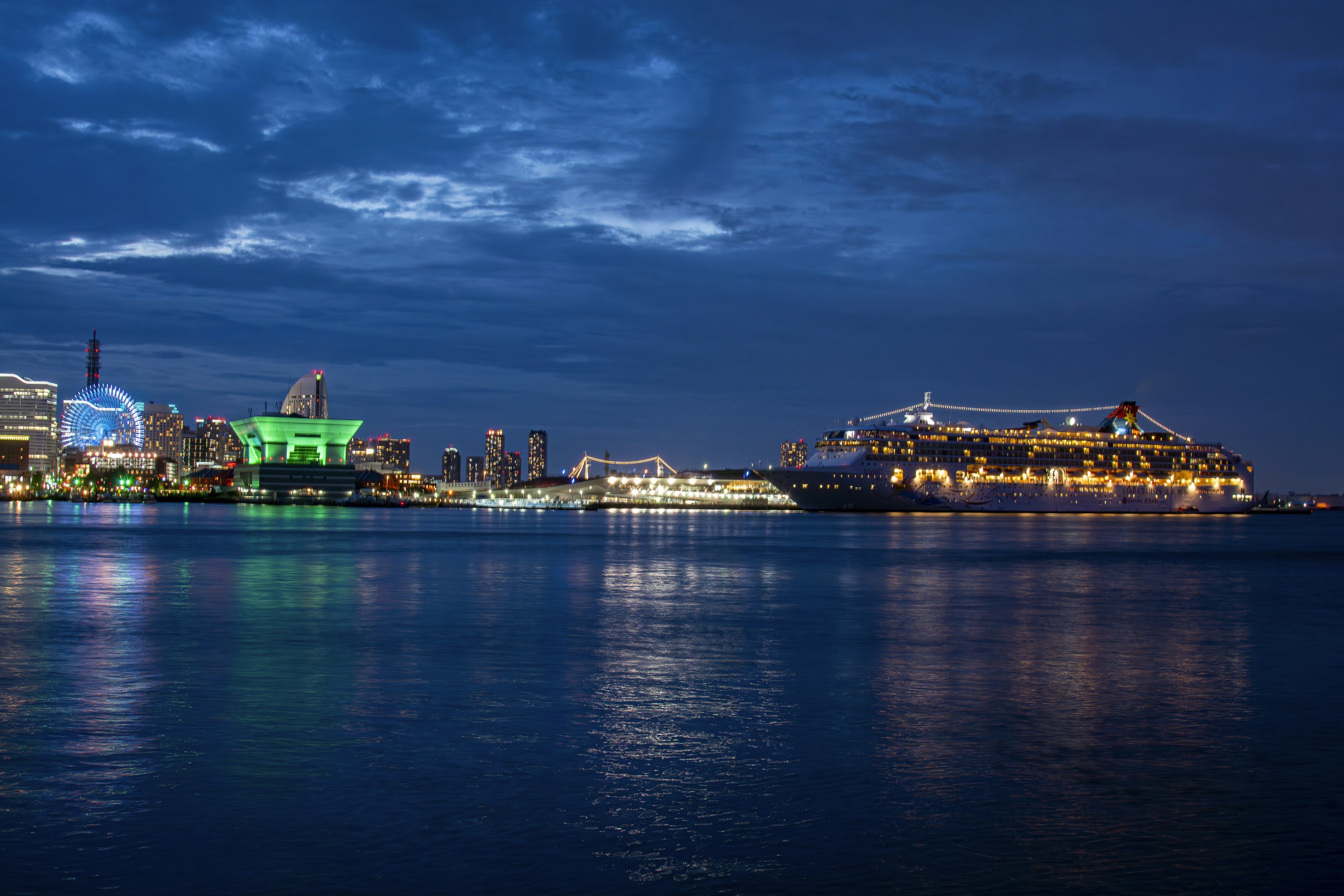 Vista notturna del porto con navi e edifici illuminati