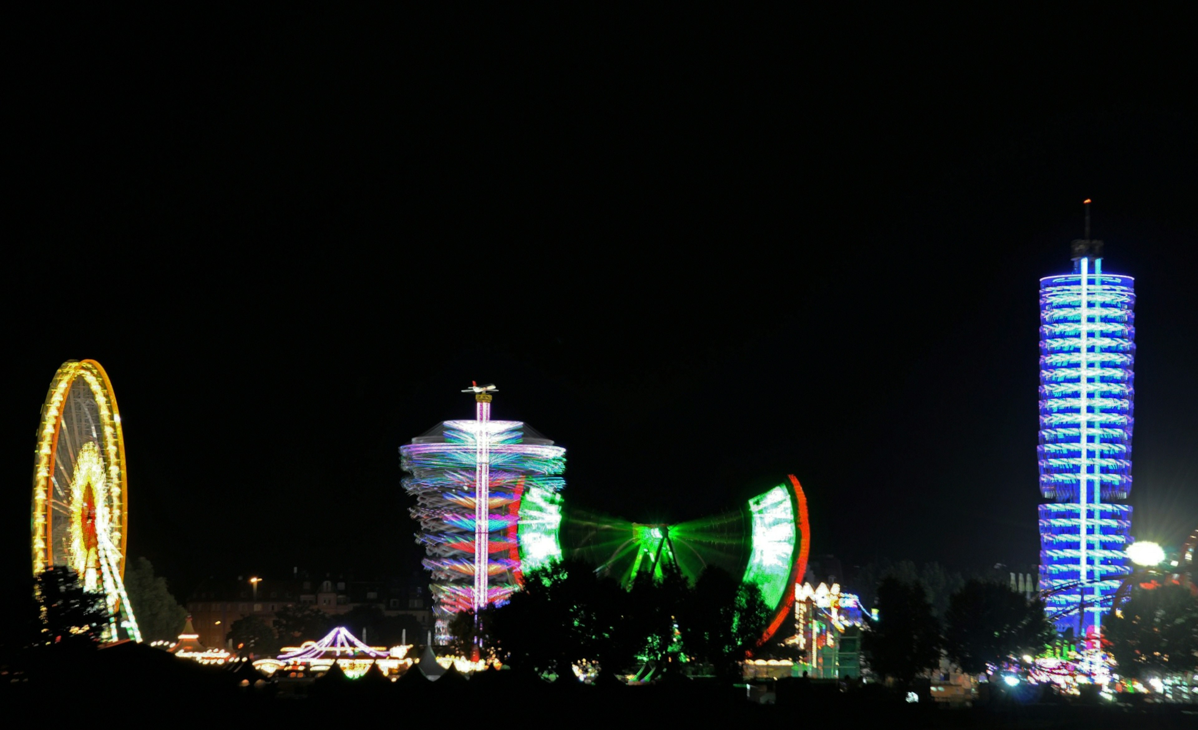 Vista nocturna de un carnaval con una noria y torres iluminadas