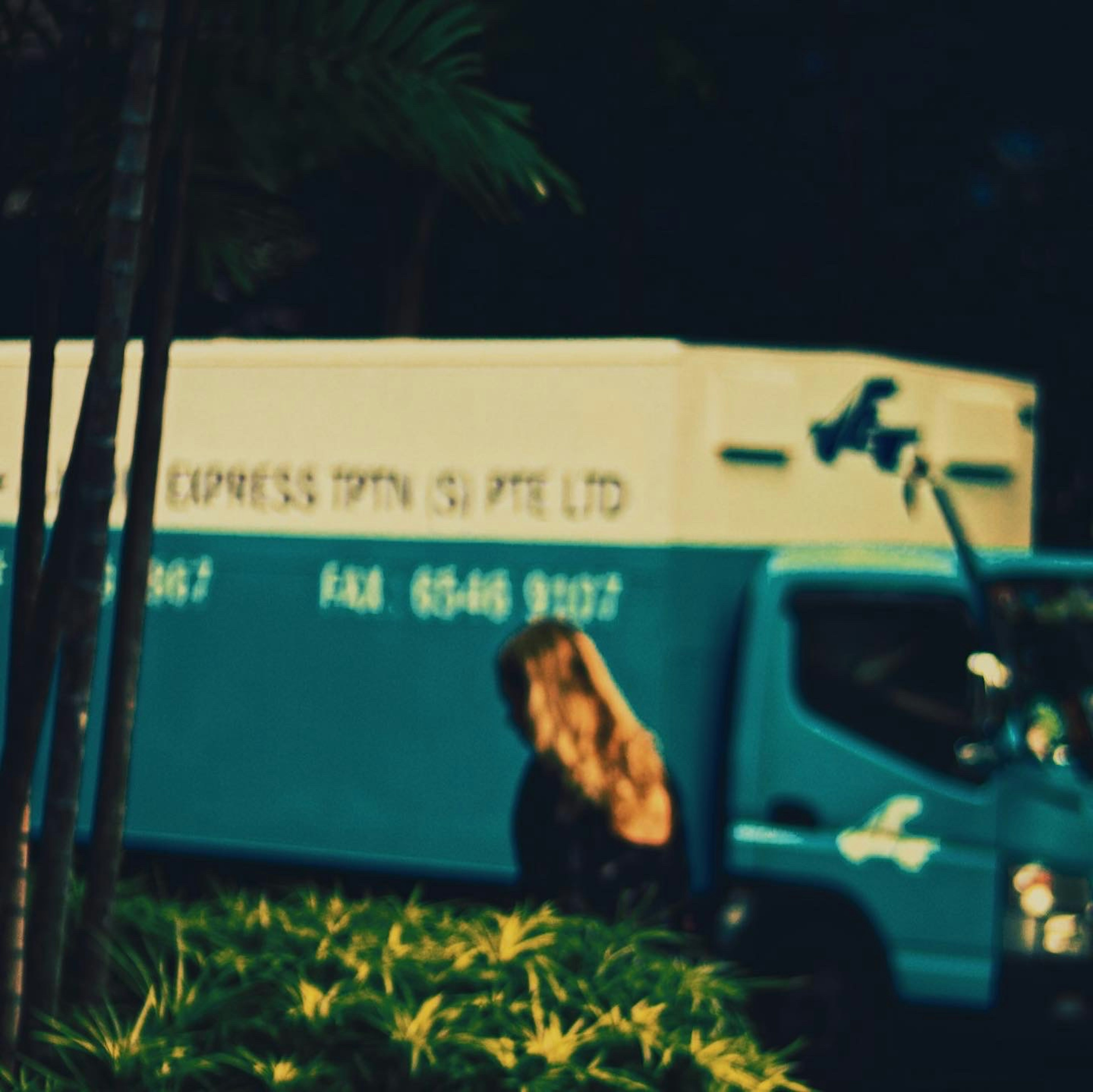 A woman walking in front of a blue delivery truck