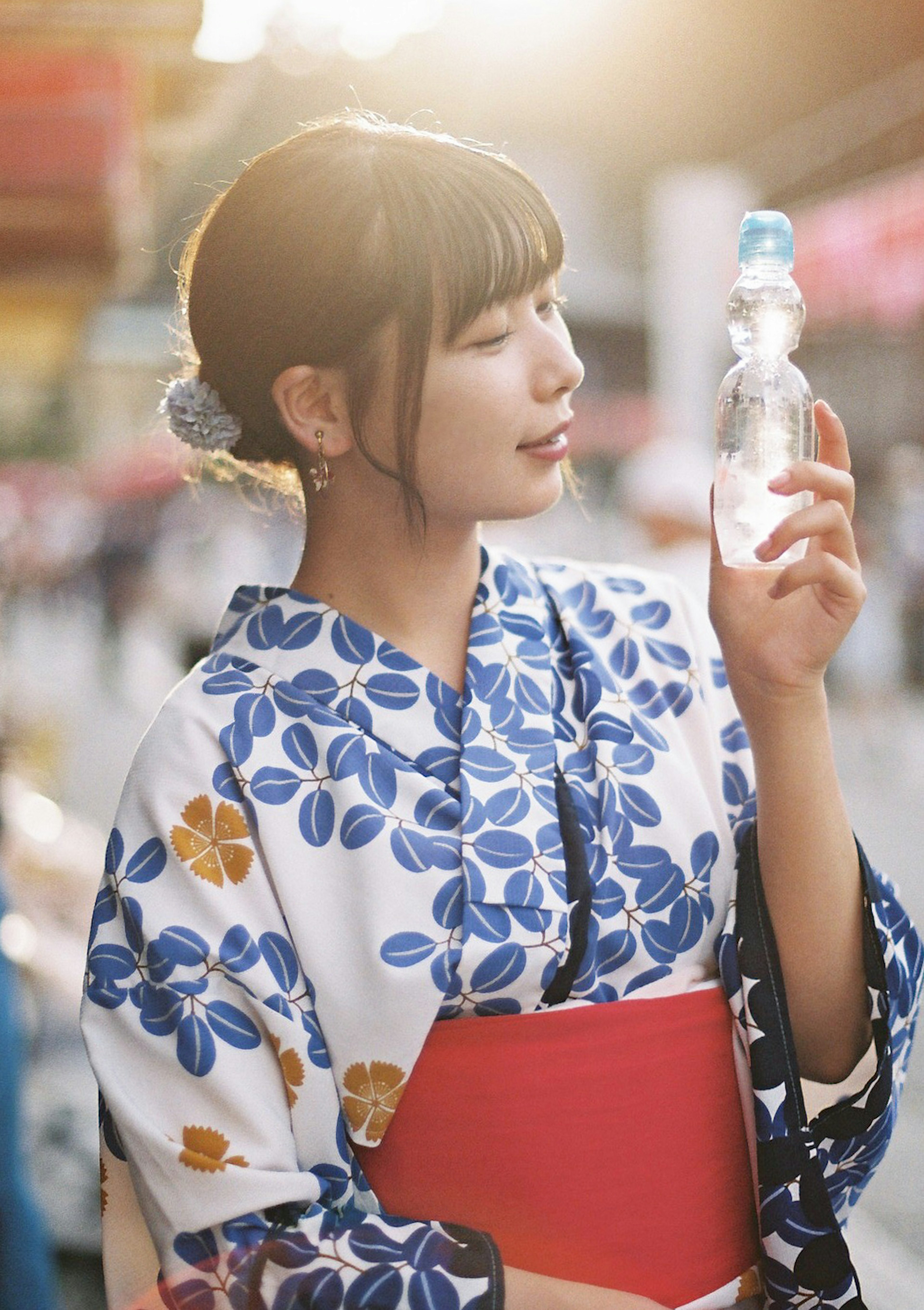 Seorang wanita dalam kimono floral biru memegang botol air