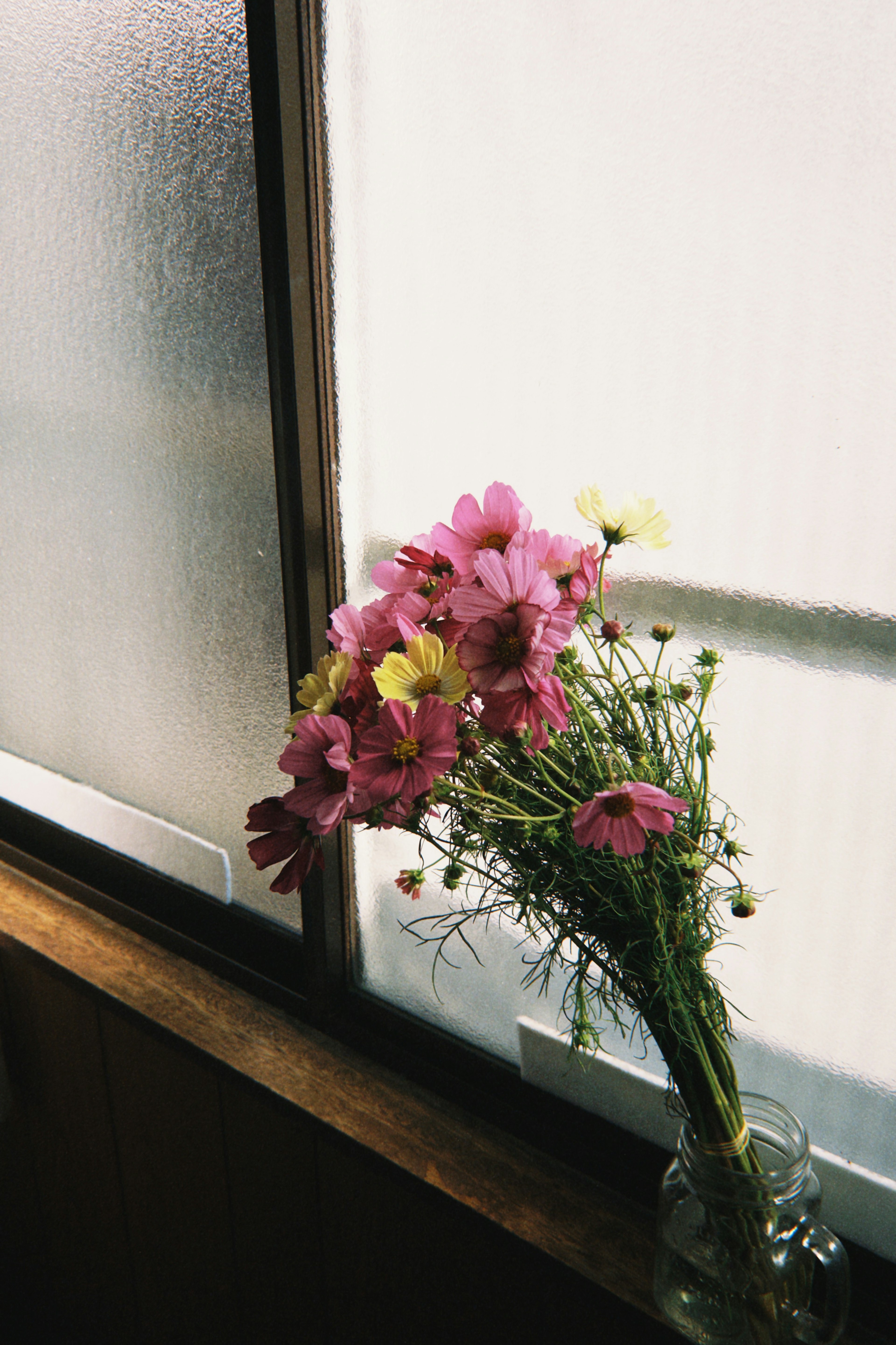 A bouquet of pink flowers and small white blooms on a windowsill