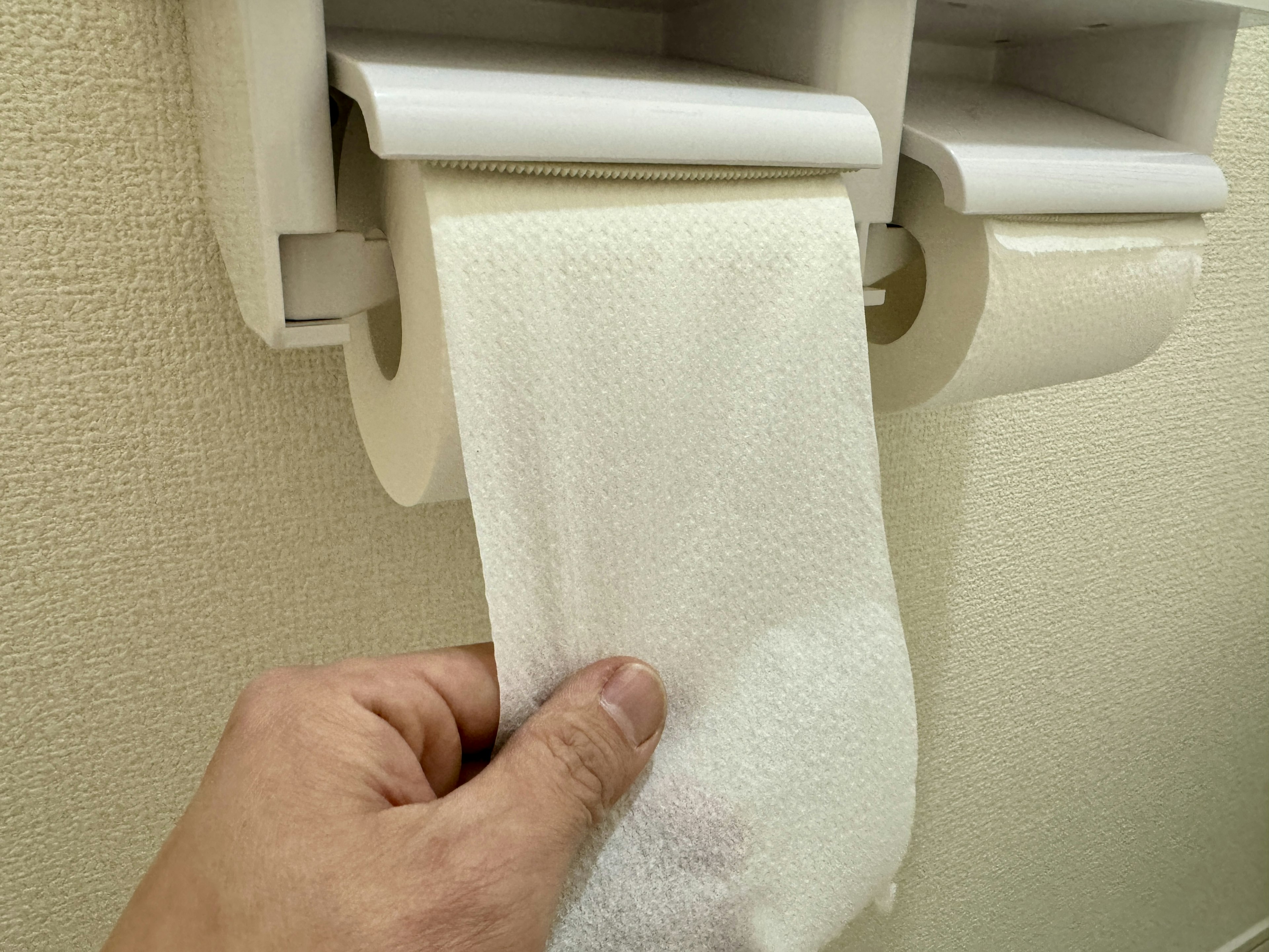 A white paper towel being dispensed from a holder