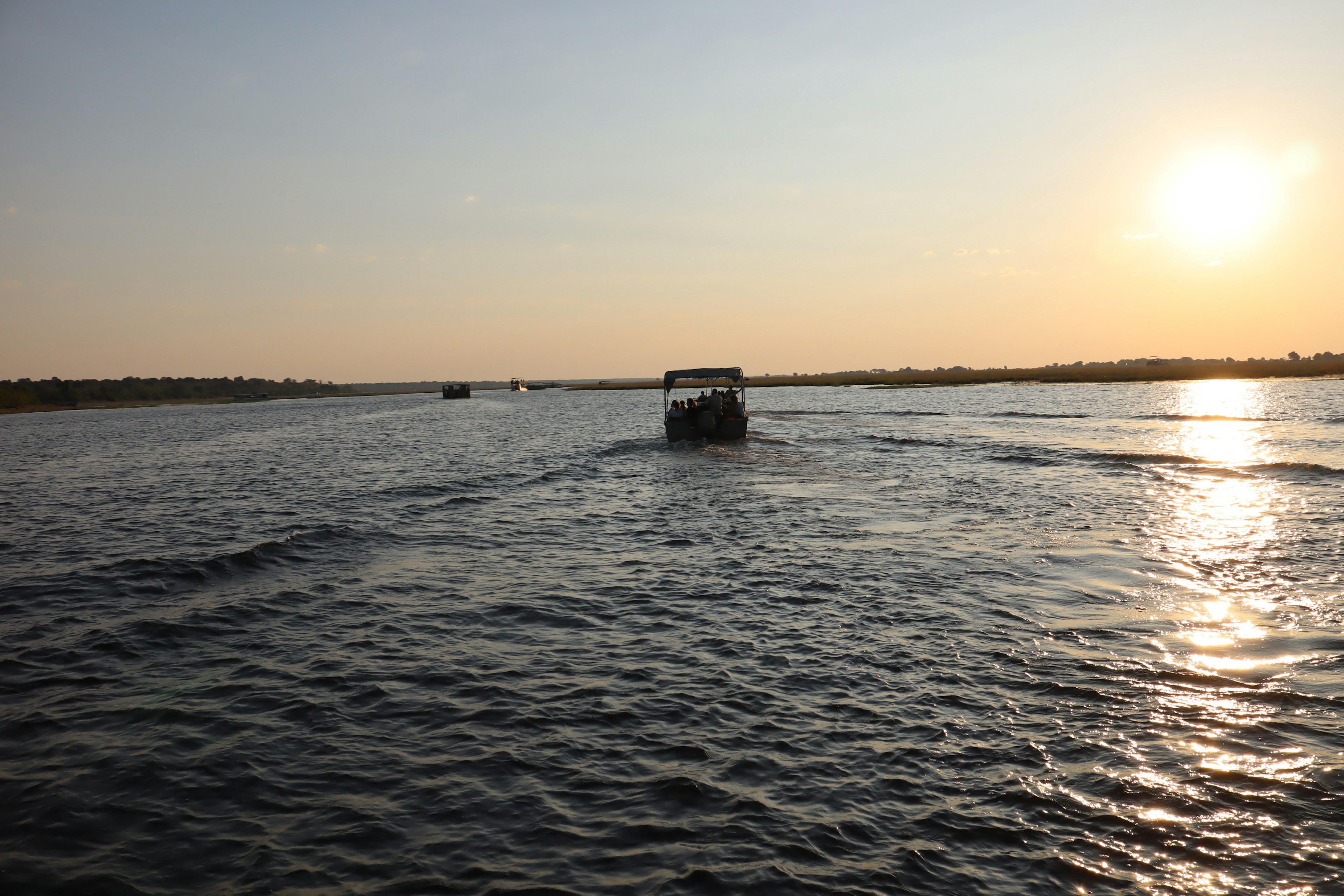 A boat moving on the water under a sunset sky