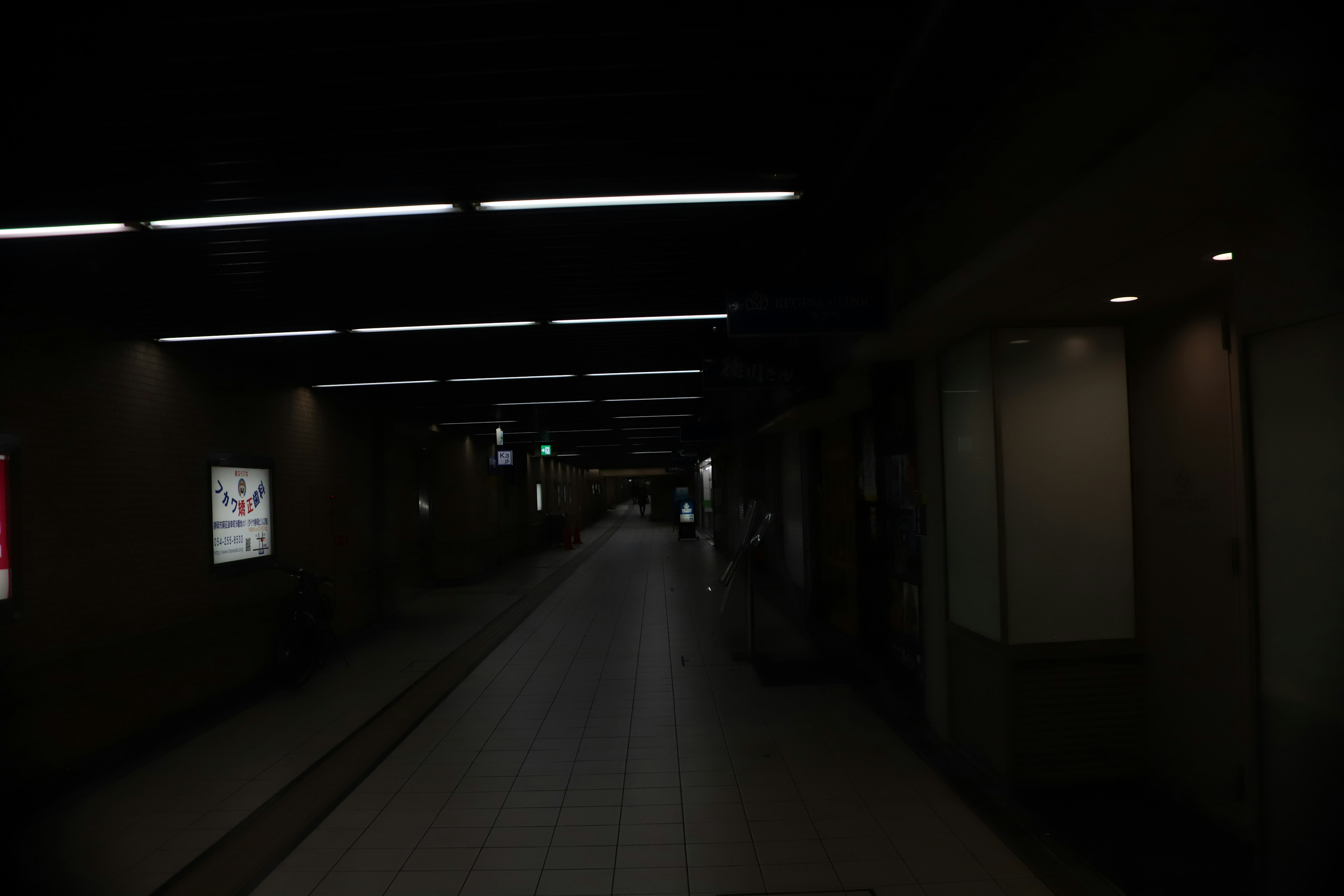 Dimly lit corridor with bright overhead lights and advertisements