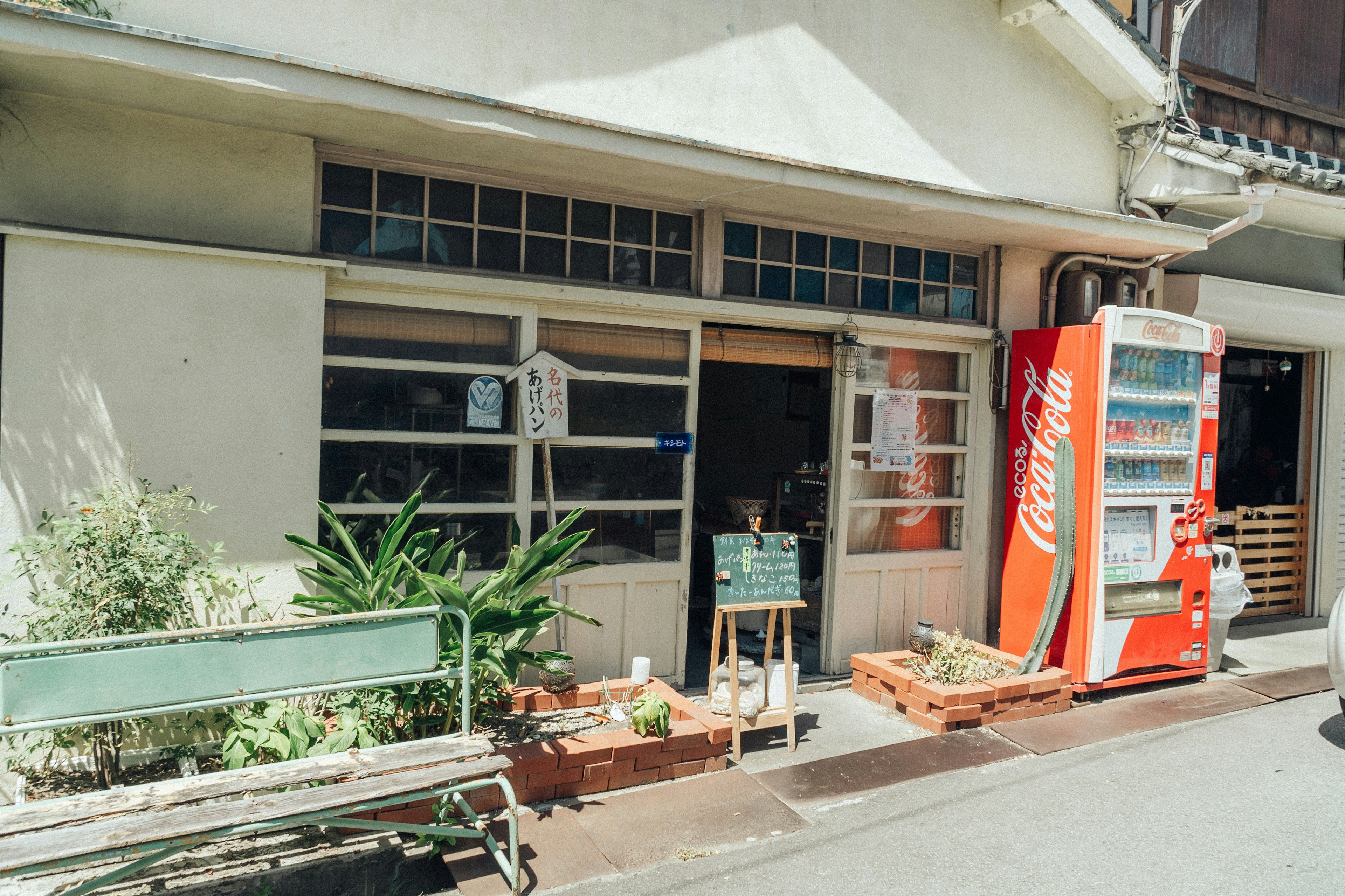 Exterior of a small shop featuring a vending machine and a bench