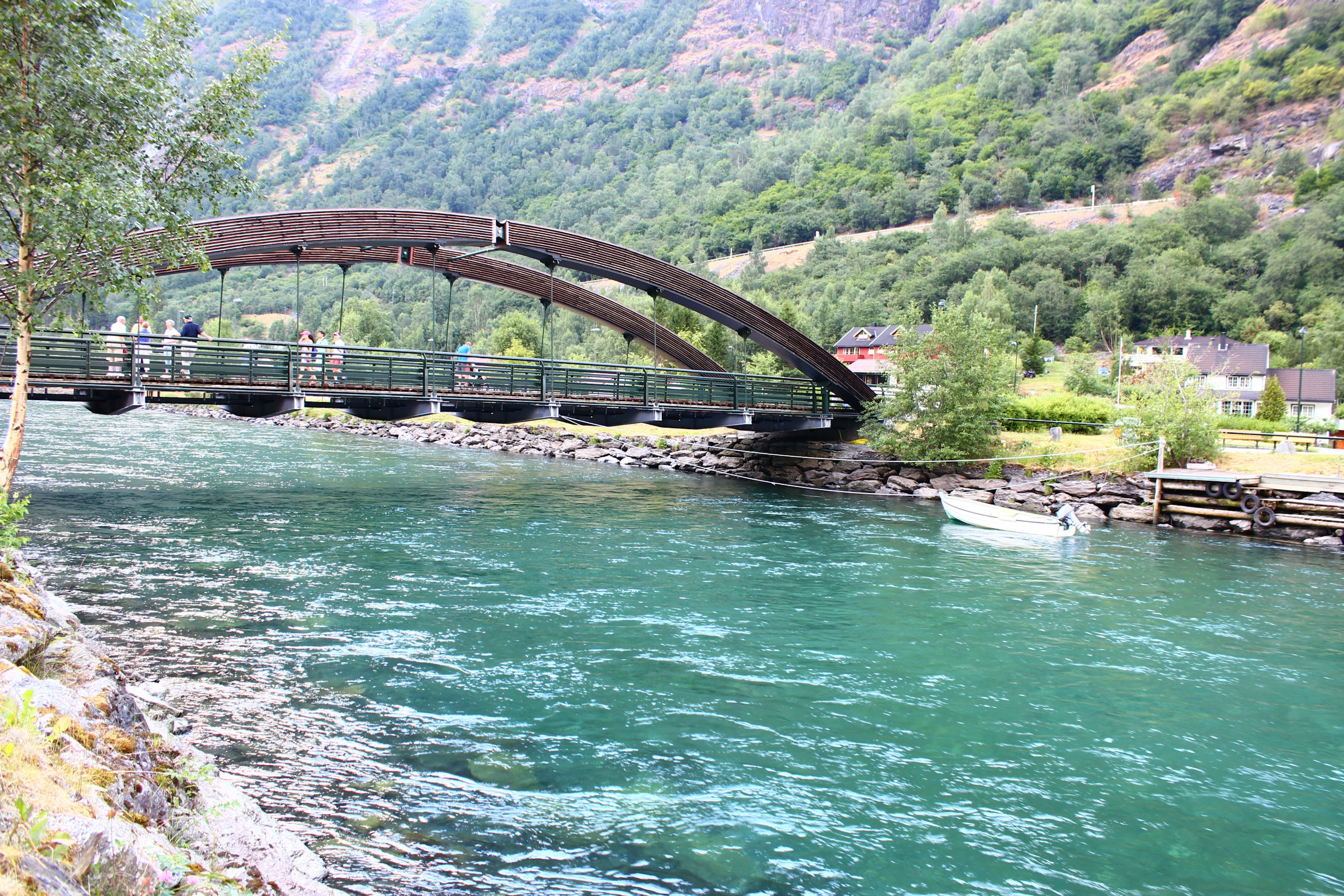 Puente de arco de madera sobre un hermoso río azul rodeado de montañas verdes