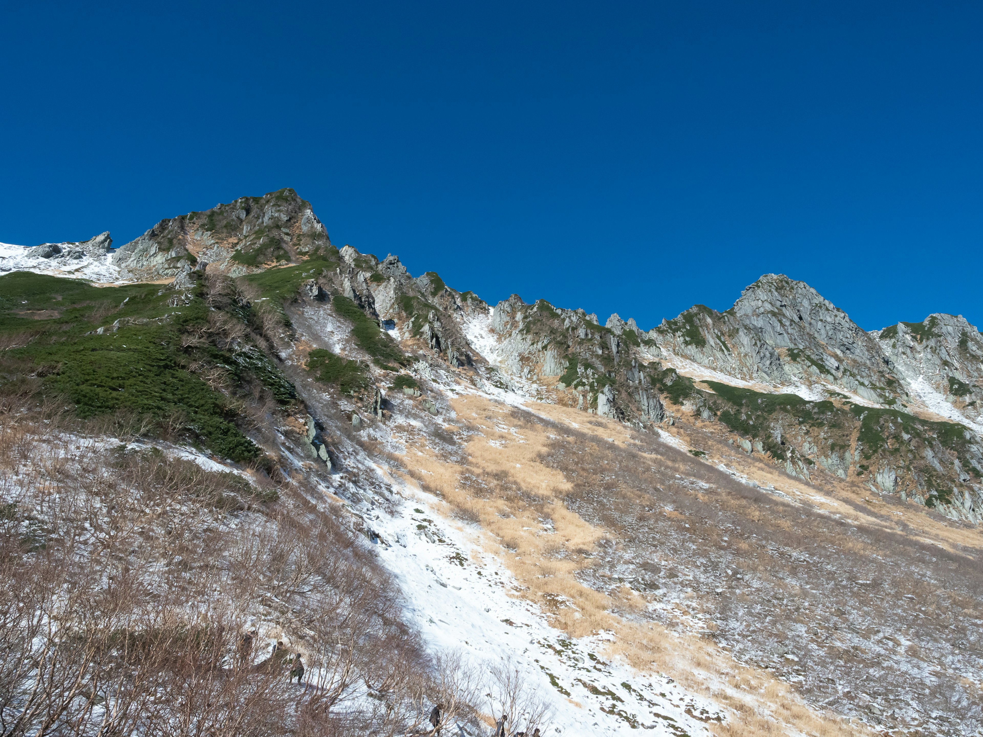 Pente montagneuse avec de la neige restante et ciel bleu clair