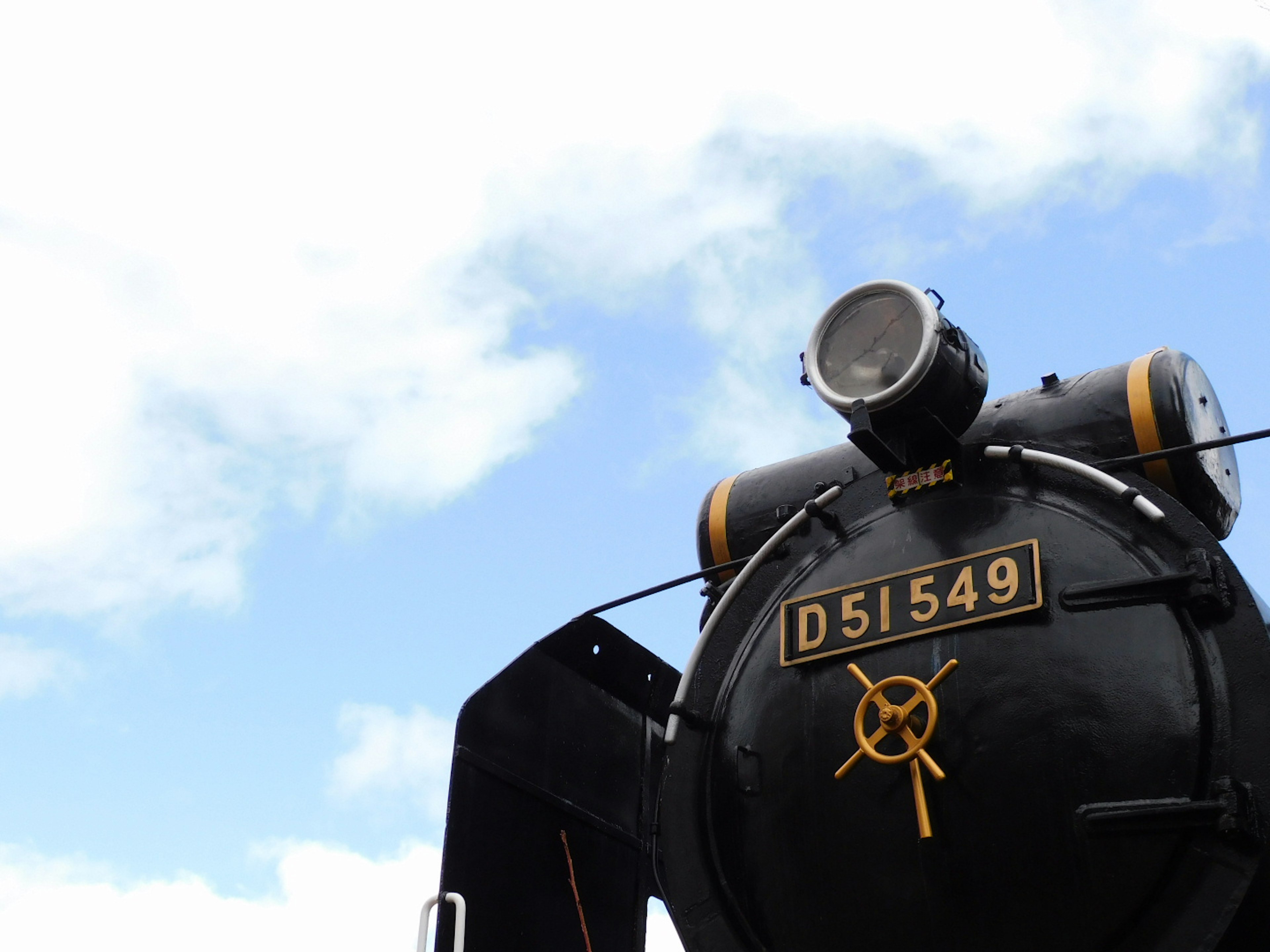 Side view of steam locomotive D51549 against blue sky