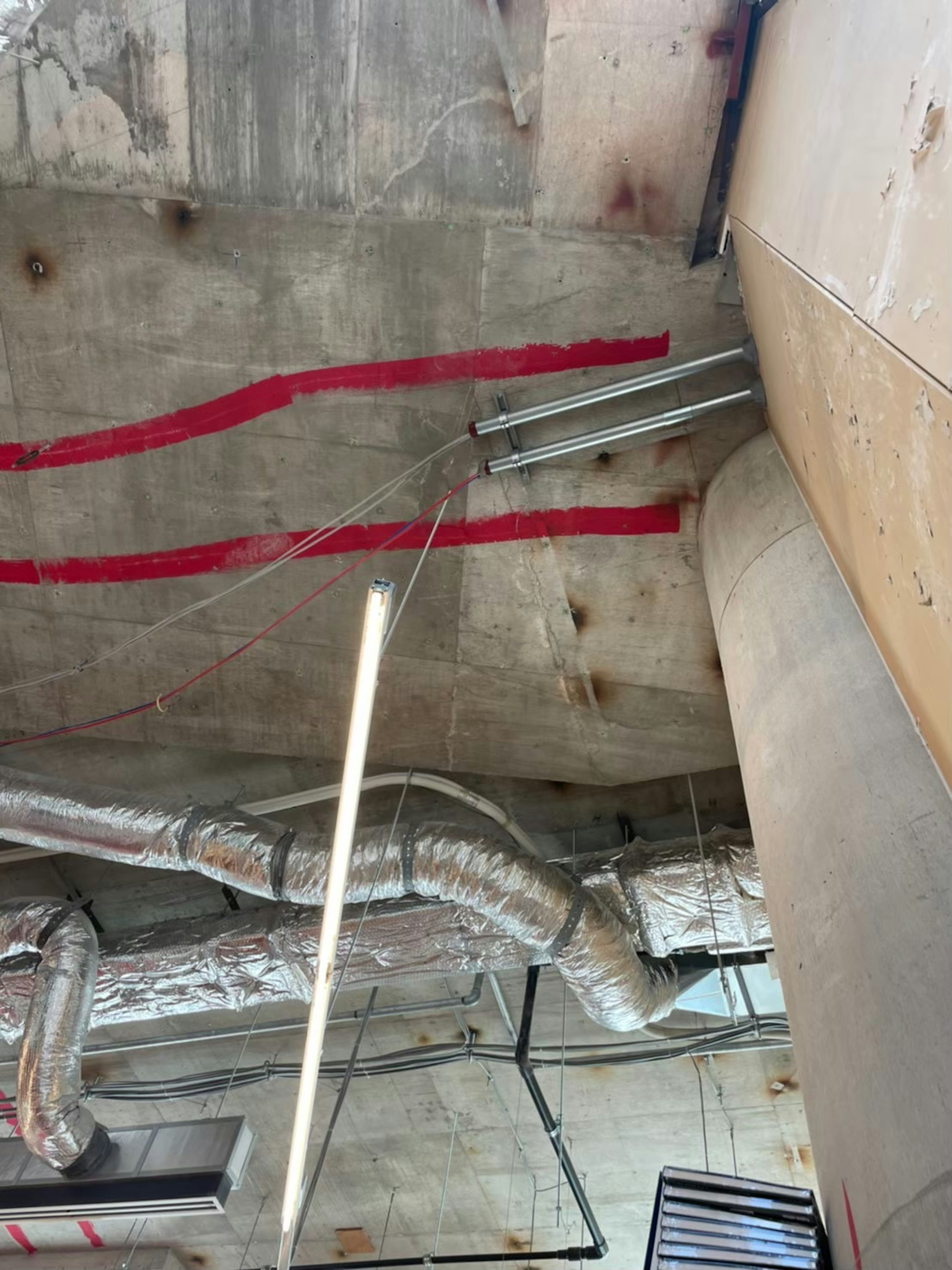 Spazio di costruzione con soffitto in cemento caratterizzato da linee rosse e tubazioni metalliche