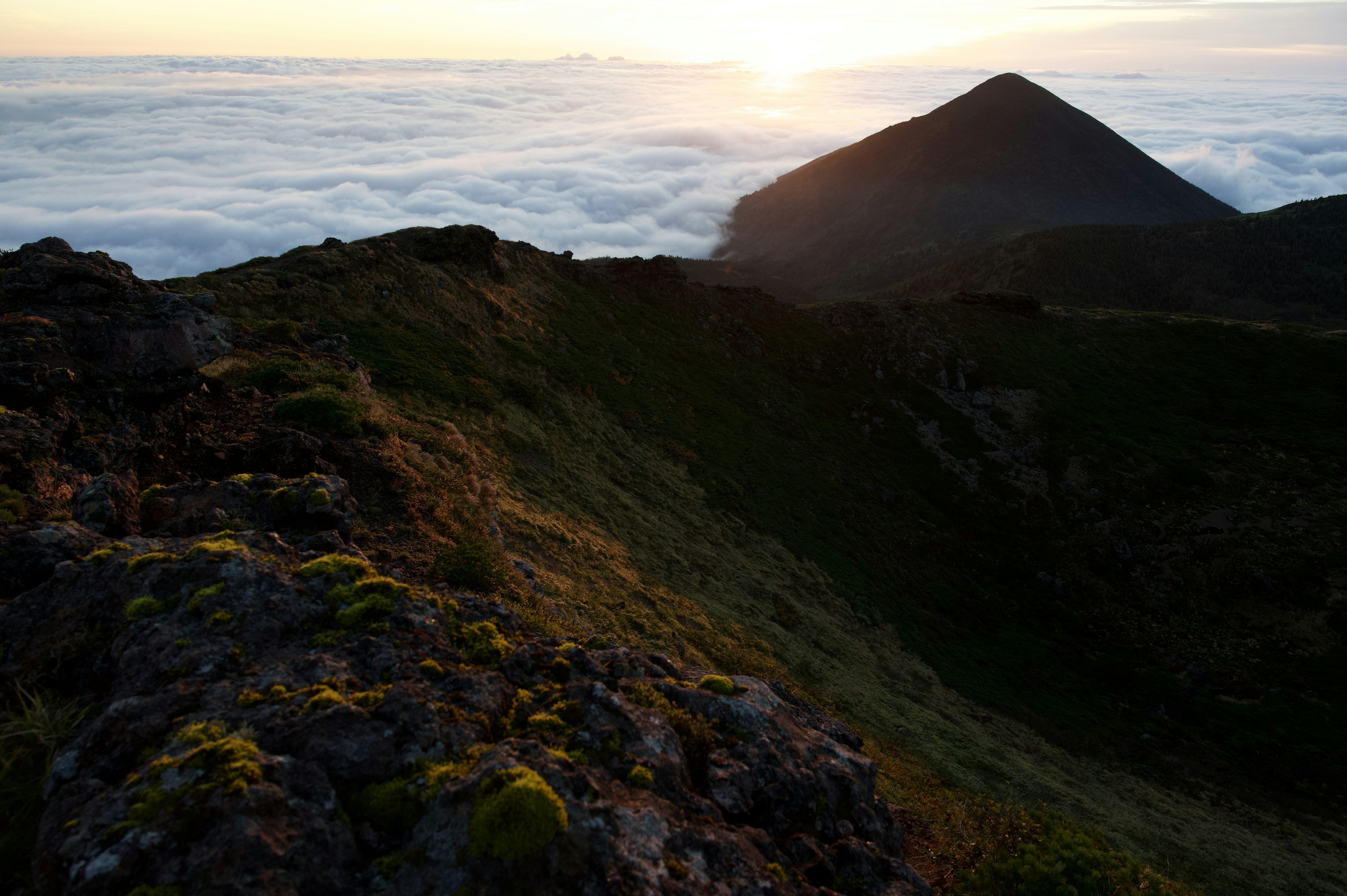 雲海の上にそびえる山のシルエットと夕日の風景