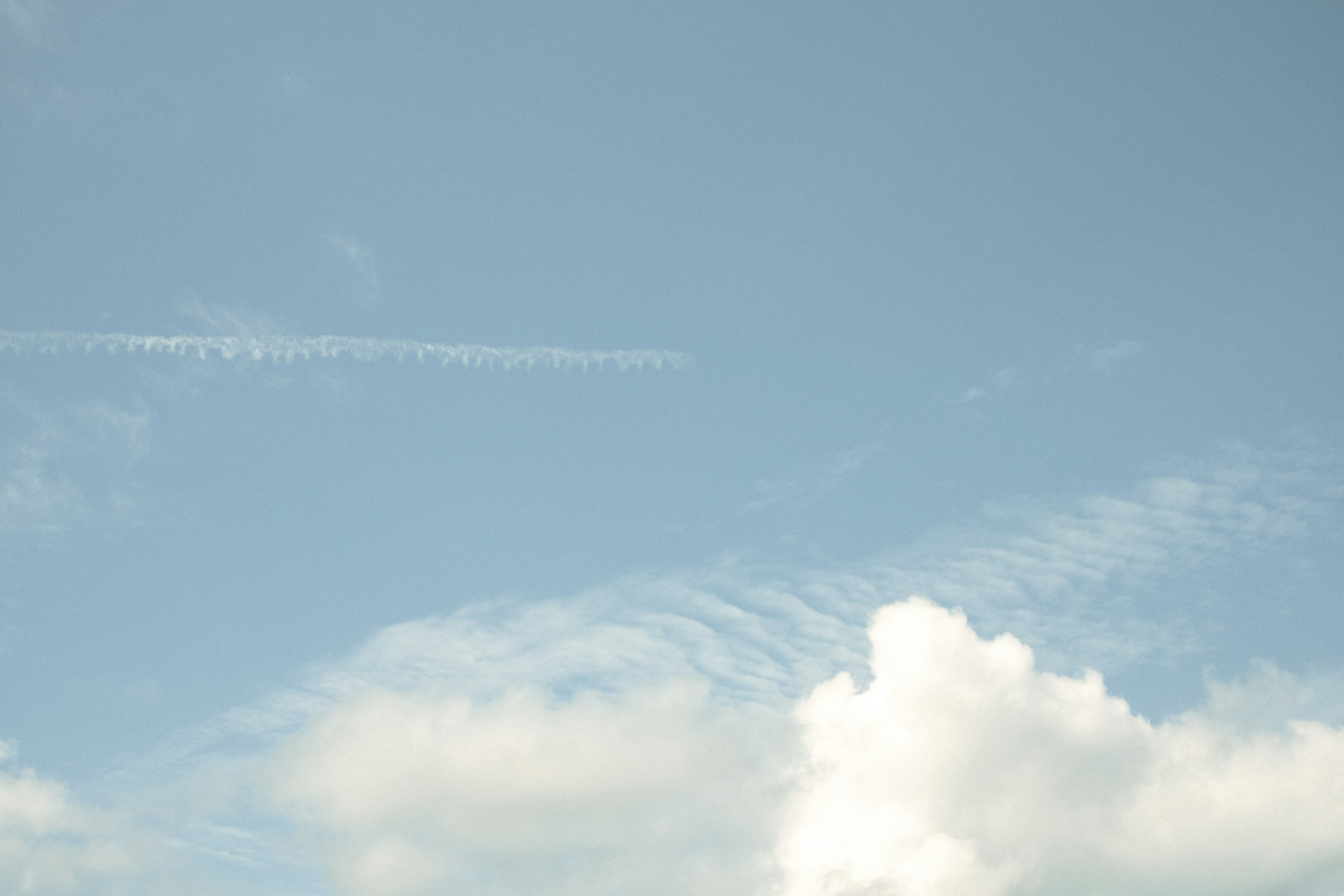 Cielo blu chiaro con nuvole bianche e scie di aerei