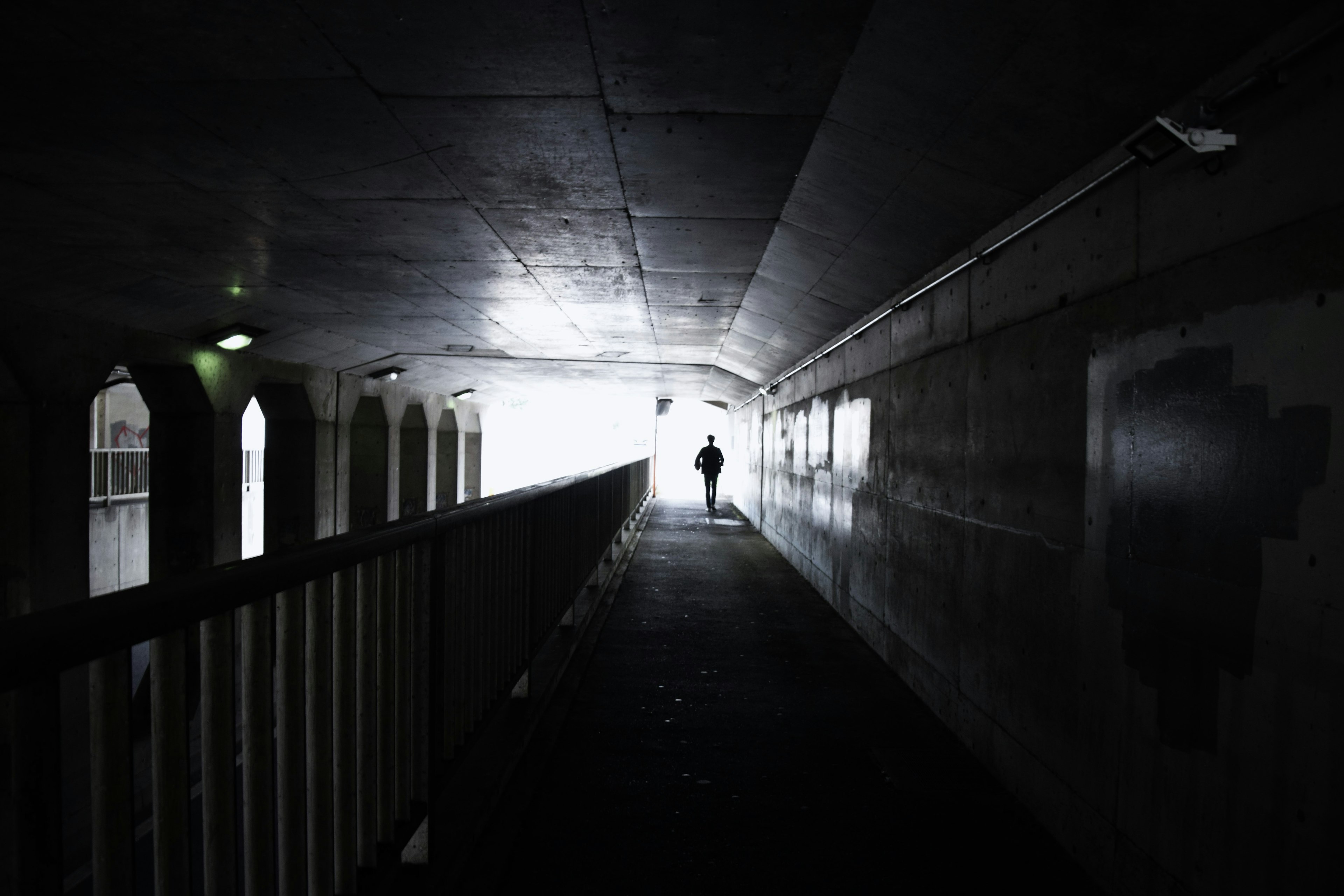 Silhouette of a person standing at the end of a dimly lit tunnel