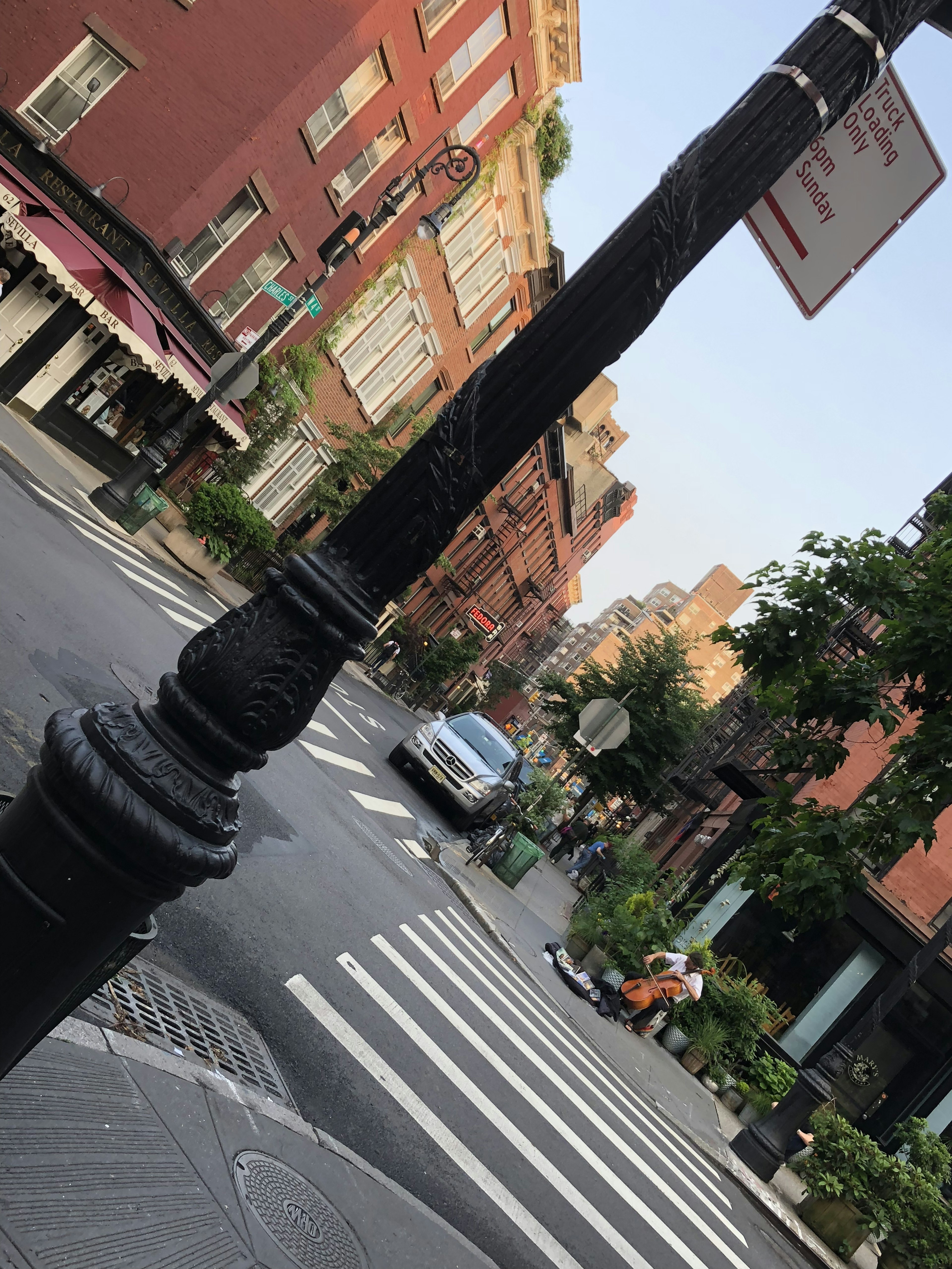 Street corner with a crosswalk and sidewalk featuring a car and green trees